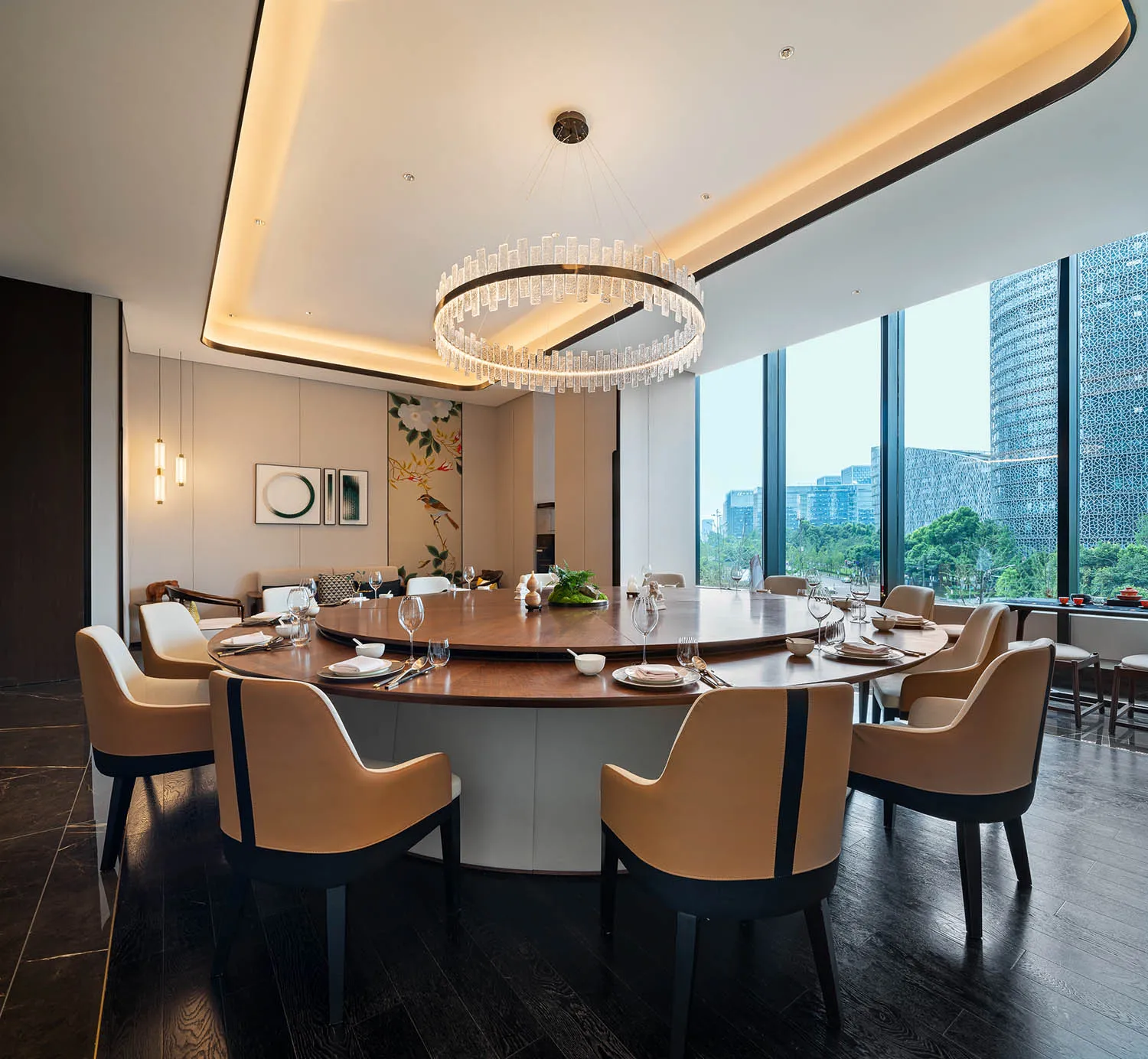 Modern dining room featuring a round wooden table with leather chairs and a large glass chandelier.
