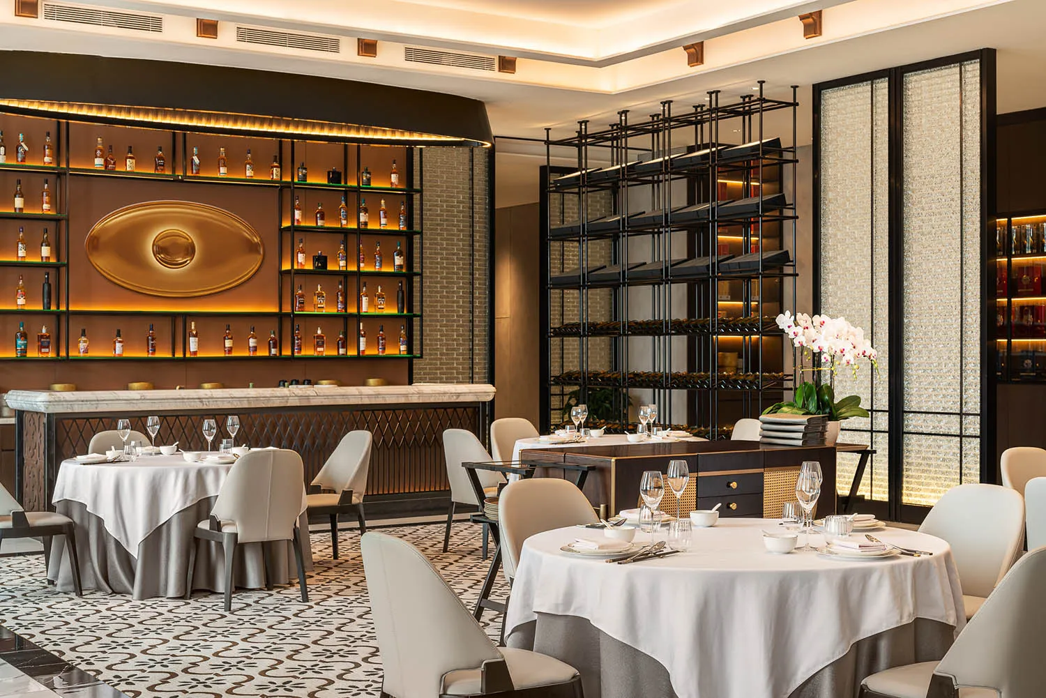 A modern fine dining restaurant with elegant interiors, white tablecloths, and wine racks.