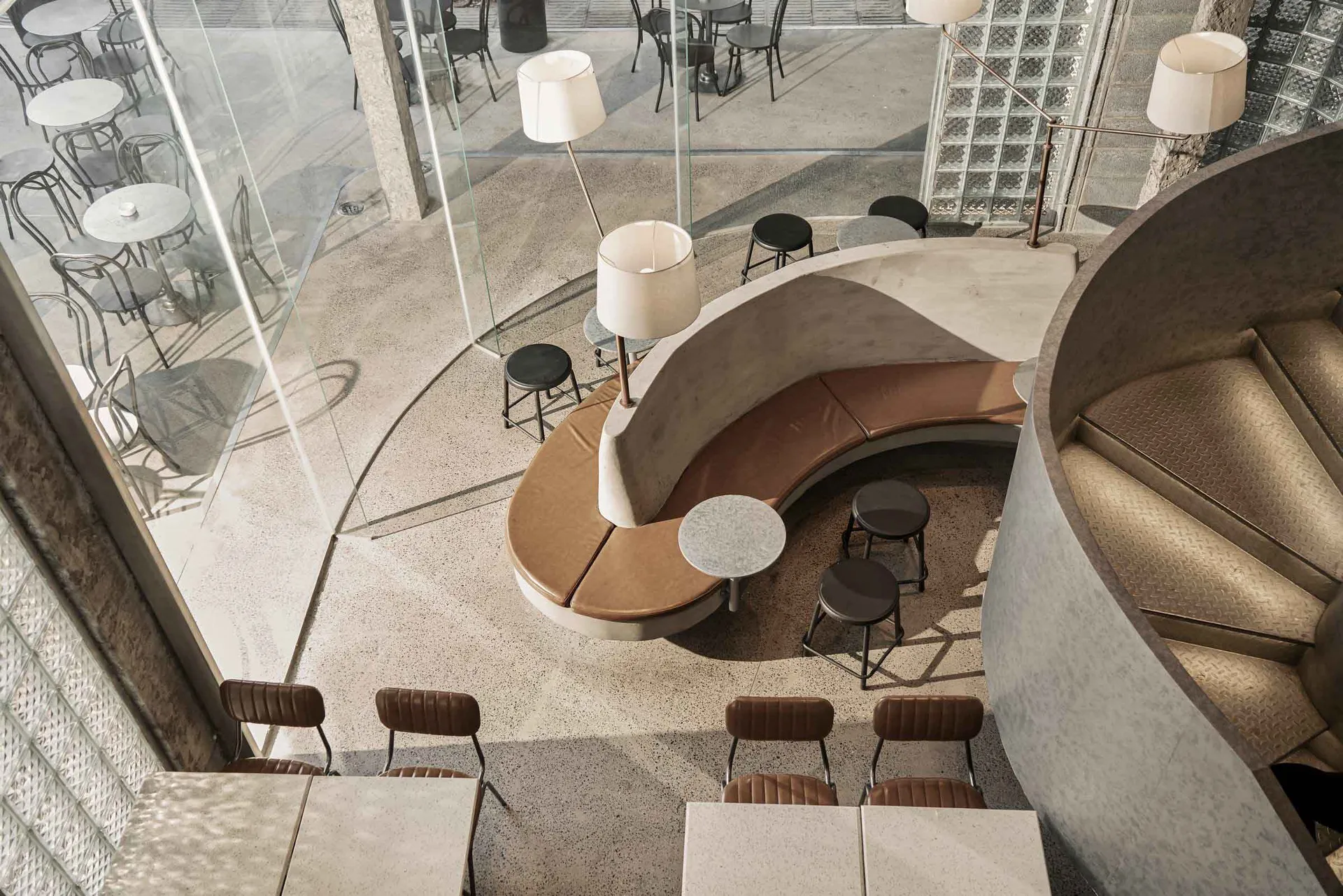 Modern industrial coffee shop with concrete seating and tables.
