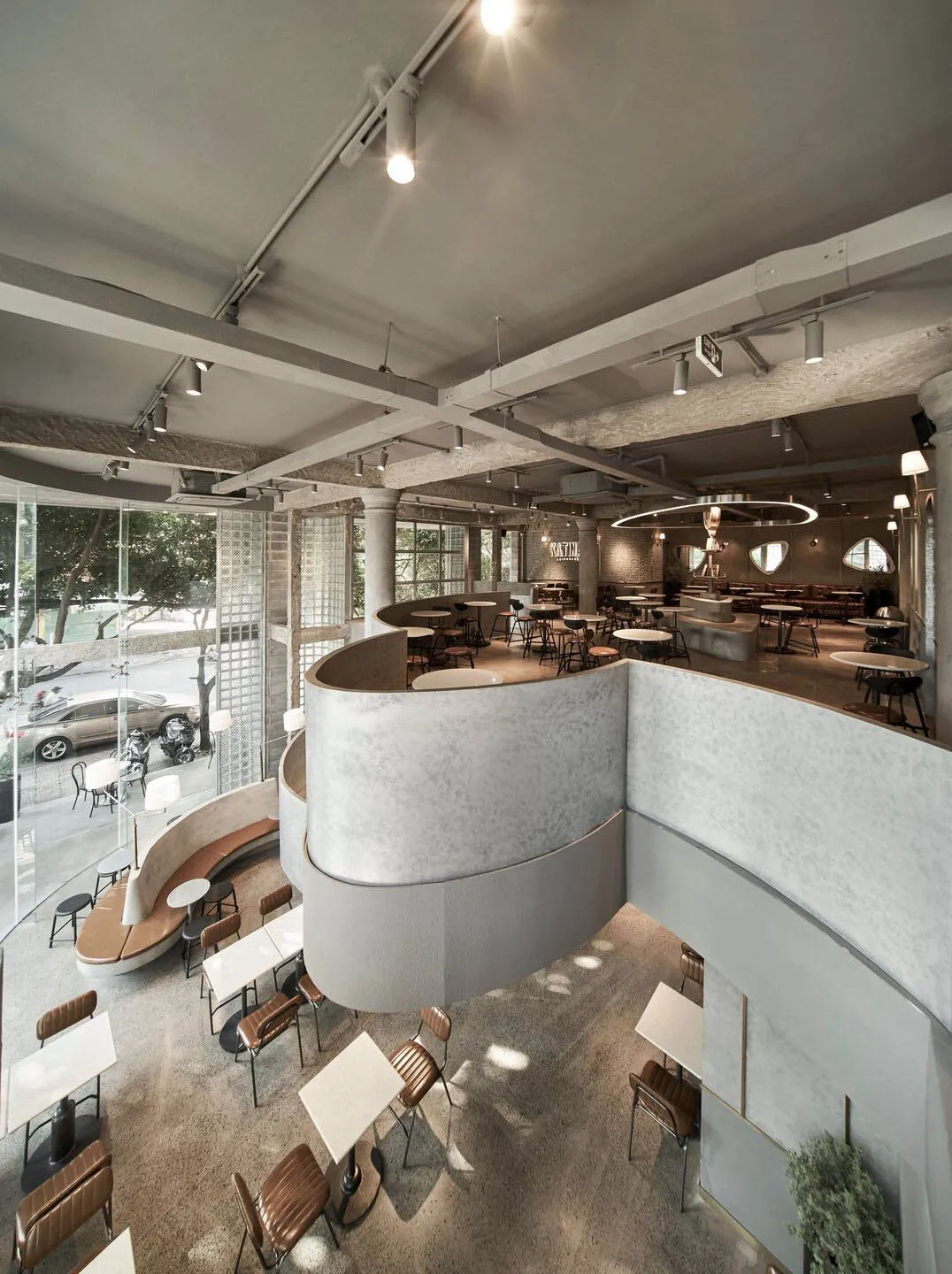 A modern, minimalist coffee shop with concrete walls and floor, featuring contemporary furniture and a spacious, open layout.