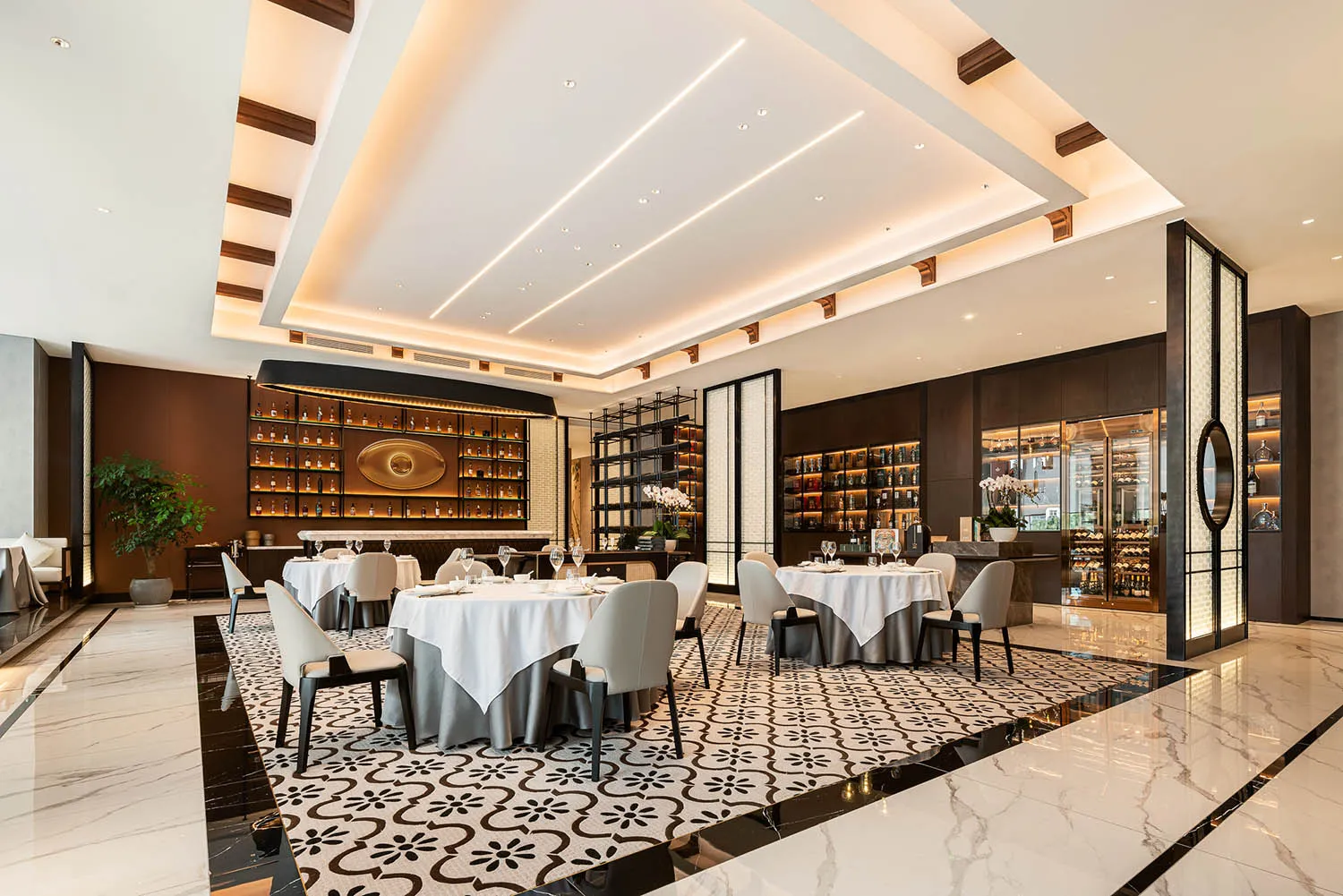 A spacious contemporary restaurant interior with marble floor tiles and elegant white dining tables.