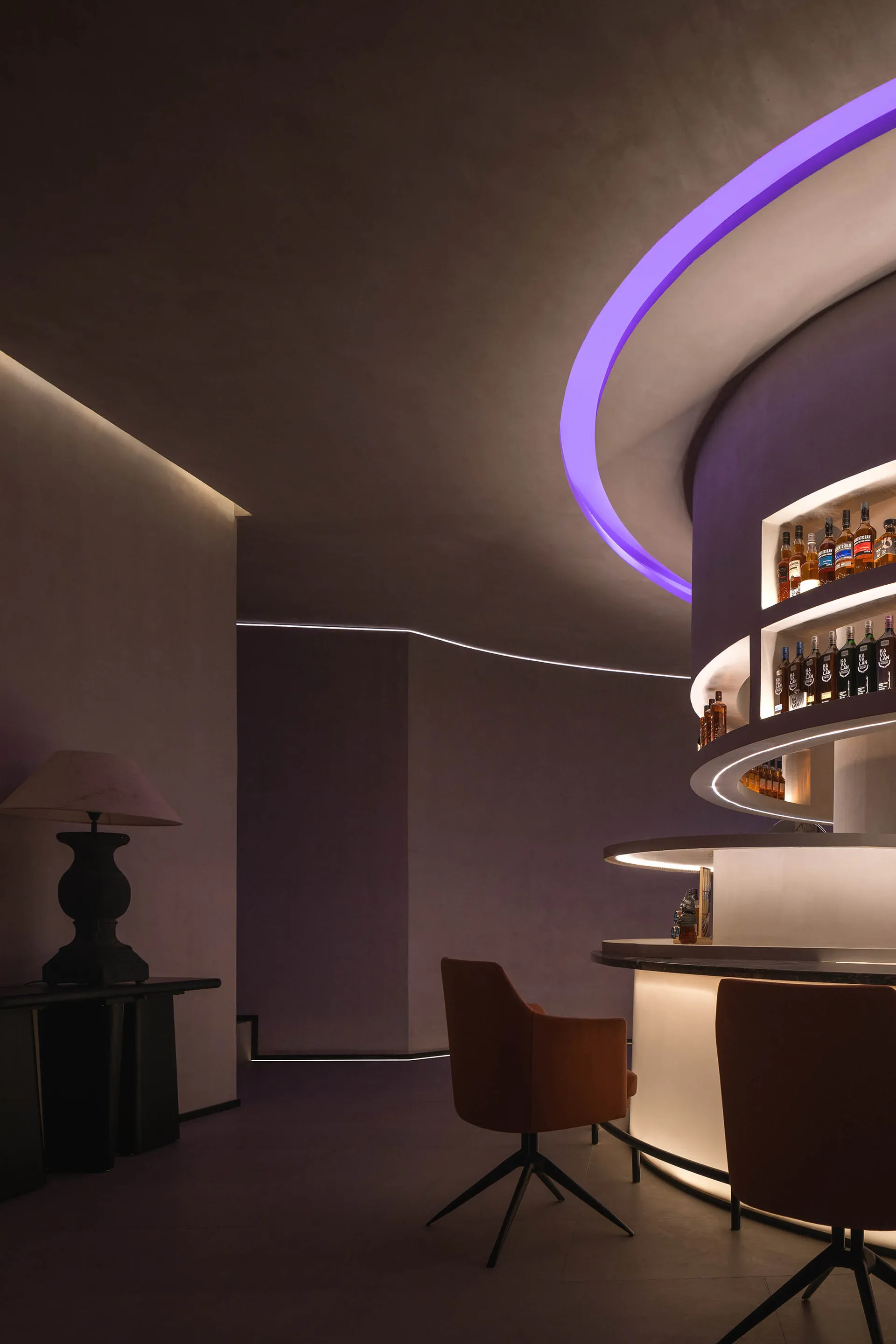 A sleek, modern bar interior with concrete walls and a circular lighting feature.