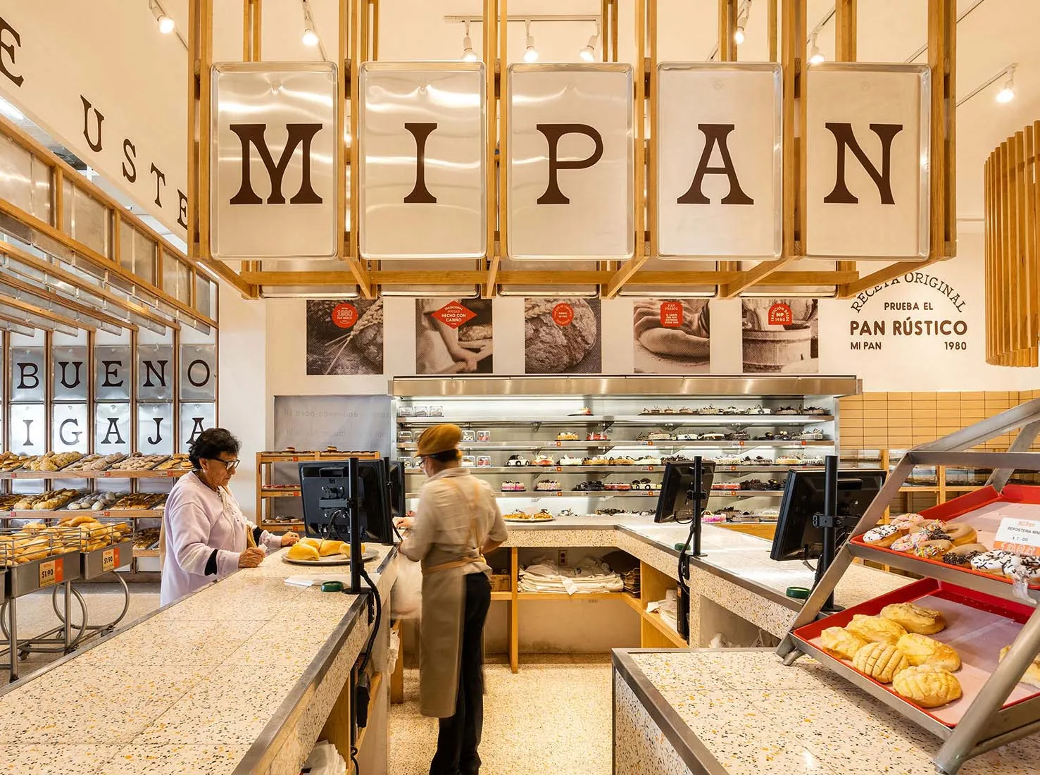 A modern retail counter in a bakery with a terrazzo countertop and shelves filled with baked goods.