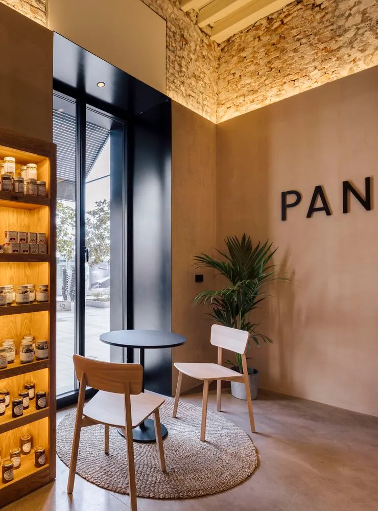 A modern cafe interior with wooden furniture and a plant.