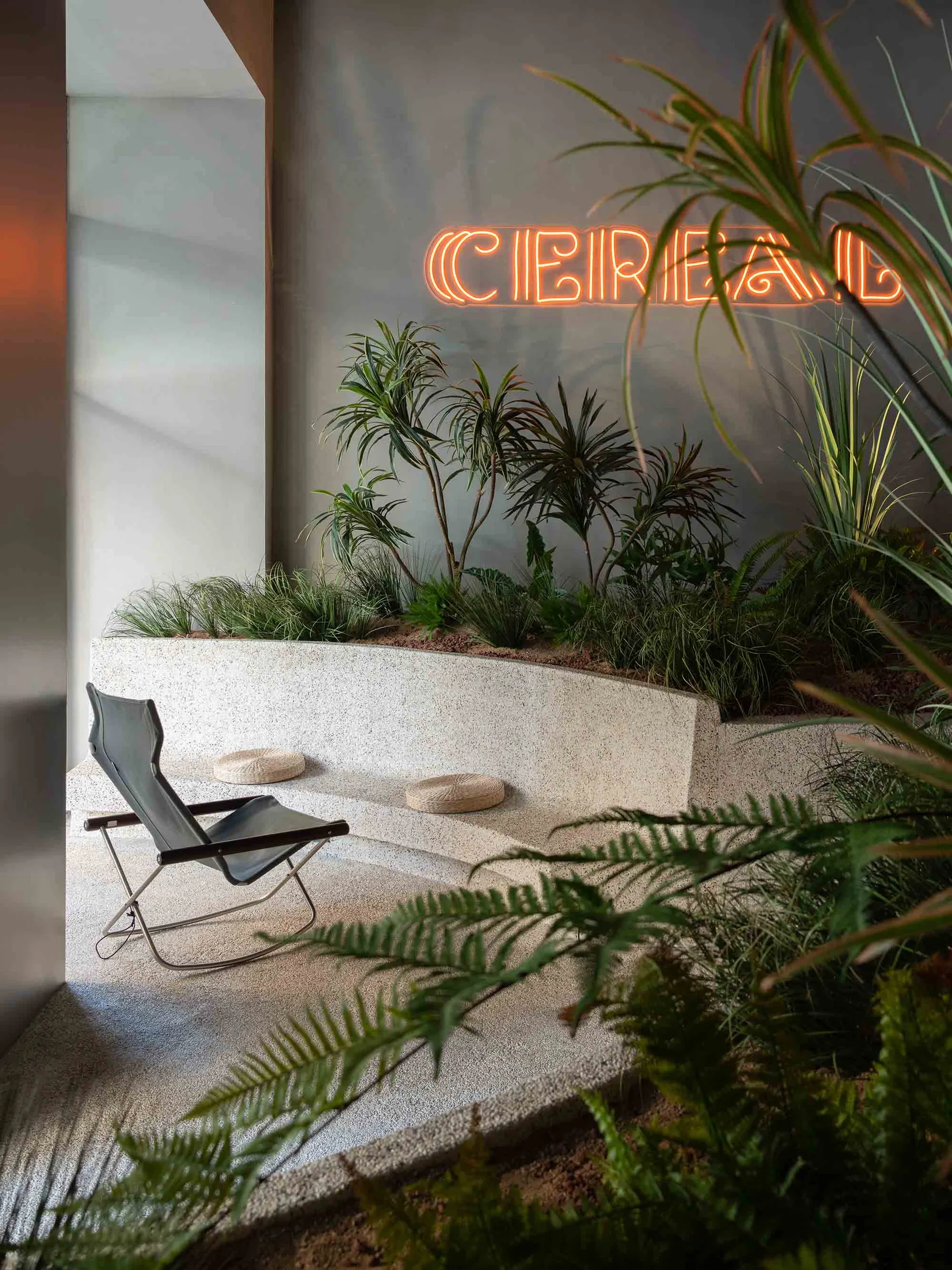 A minimalist industrial restaurant interior featuring concrete flooring and a terrazzo counter top.