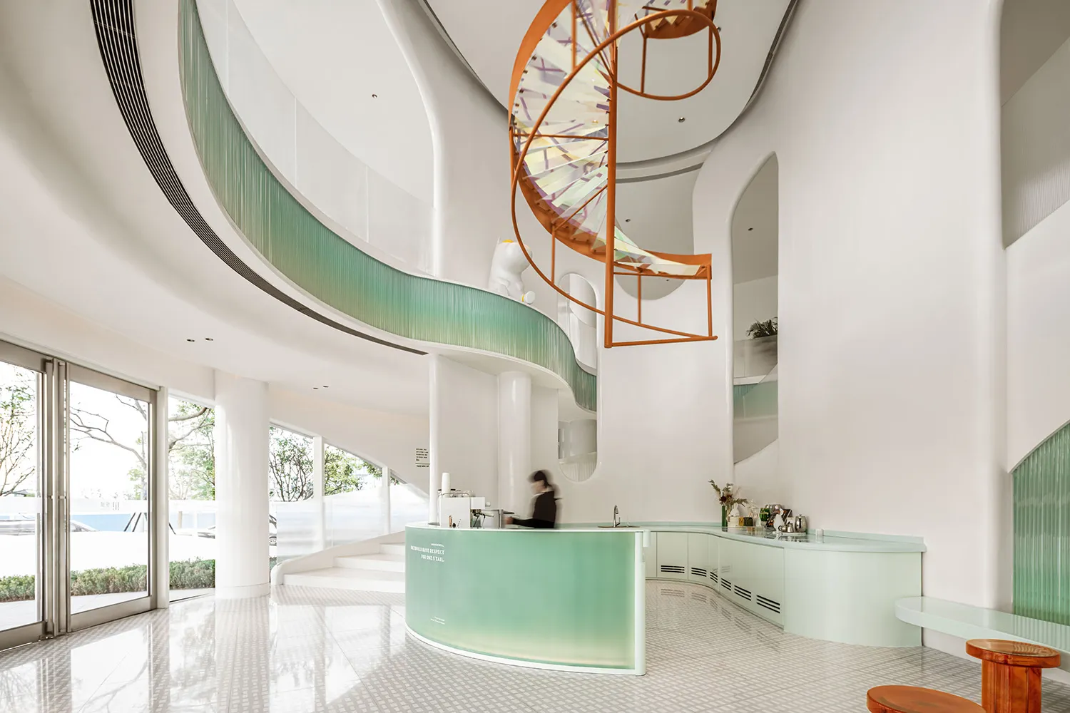 A modern coffee shop with a glass counter and spiral staircase.