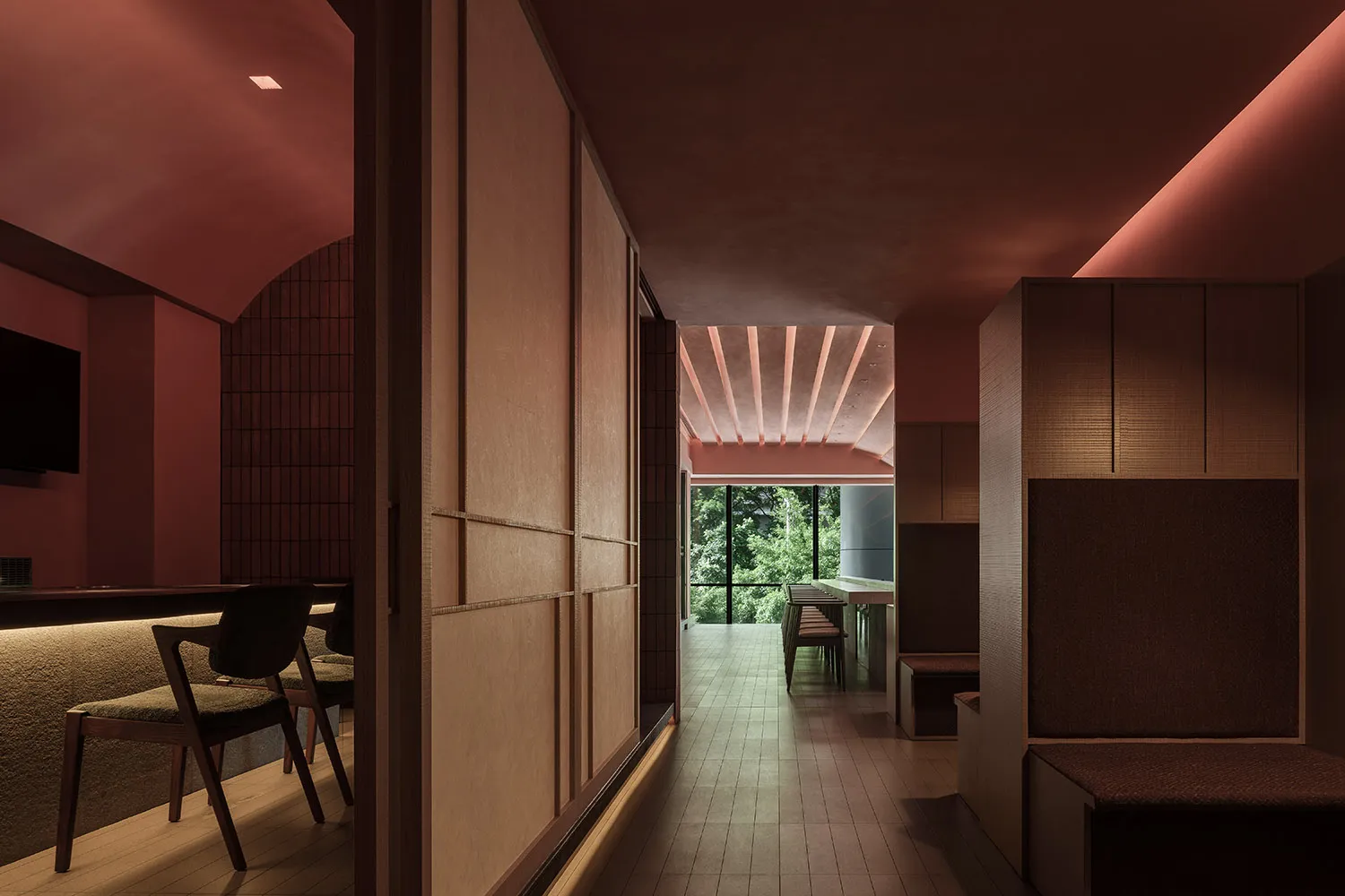 A modern restaurant interior featuring wooden walls, a red ceiling with embedded lighting, and a view of greenery through lar