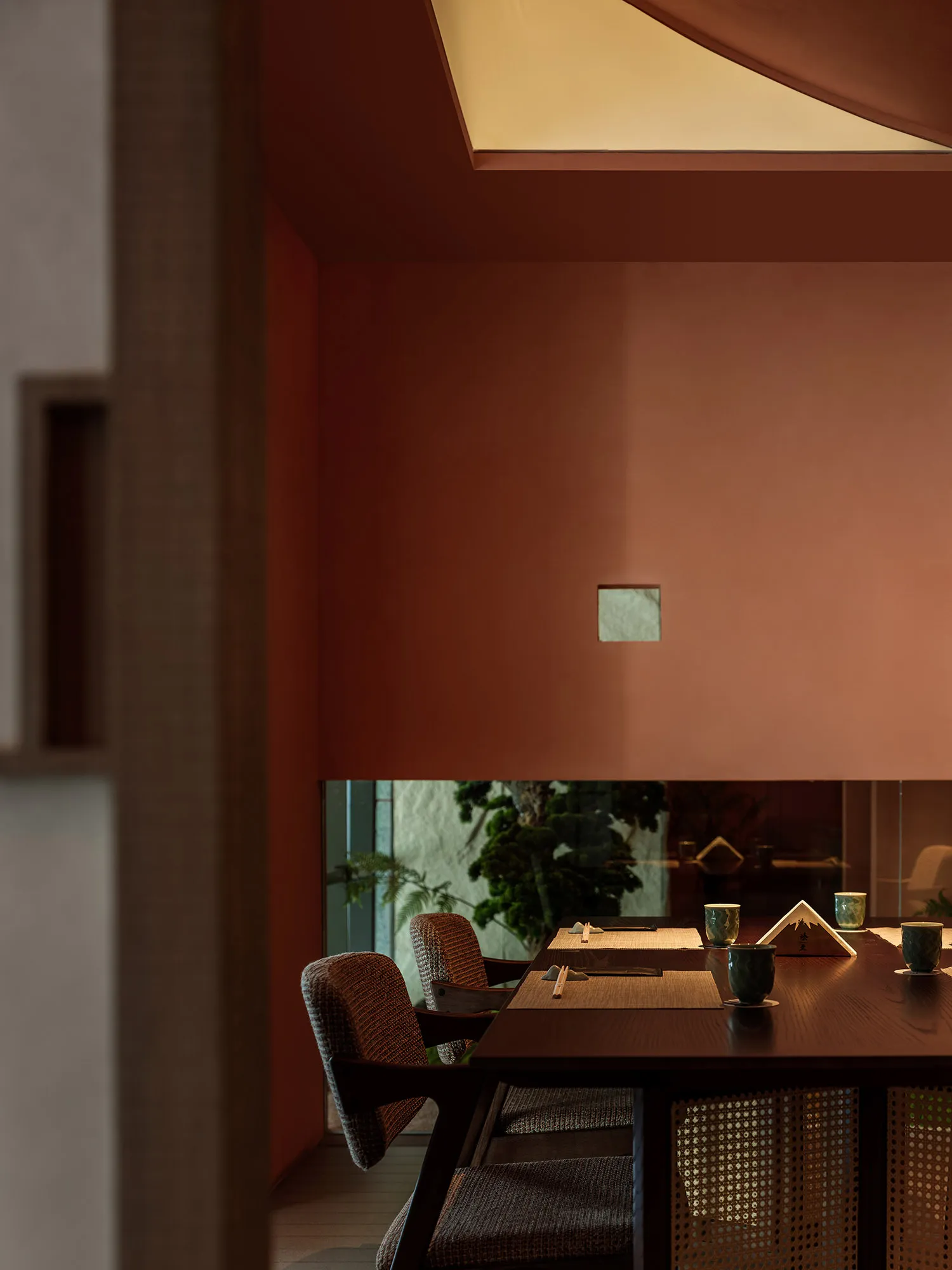 現代餐廳室內,木質餐桌搭配編織纖維椅,窗外可見綠意盎然。
