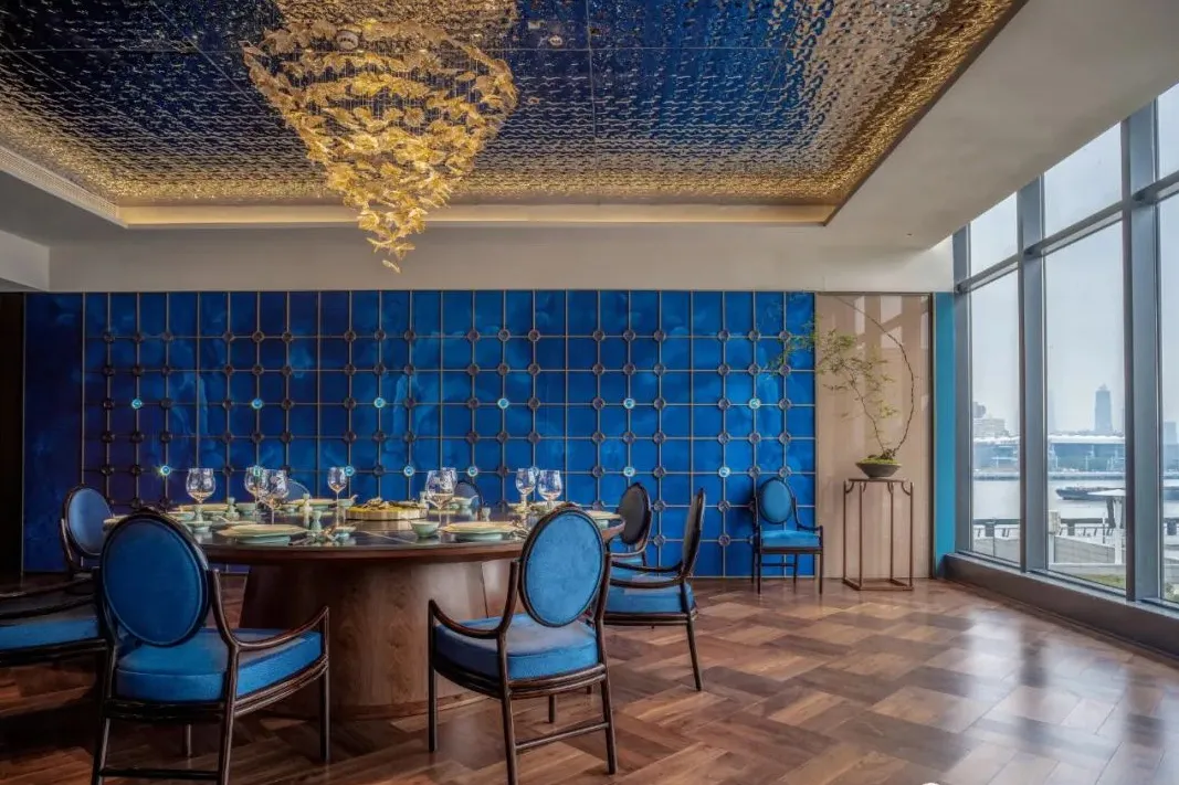 A photograph of a restaurant dining room with a blue tile backdrop, showcasing elegant dining setup and modern design.