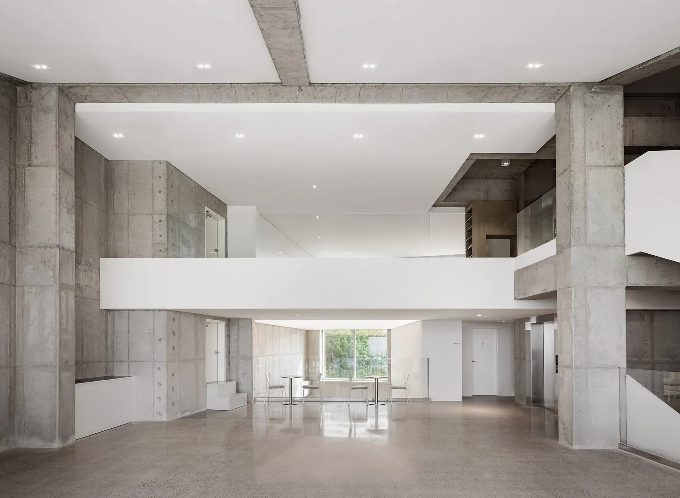 A modern lobby interior with concrete walls and ceiling, featuring a minimalist design.