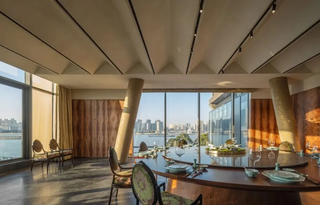 時尚餐廳室內空間，搭配金屬柱、大型玻璃窗可俯瞰城市景觀，以及餐桌座椅