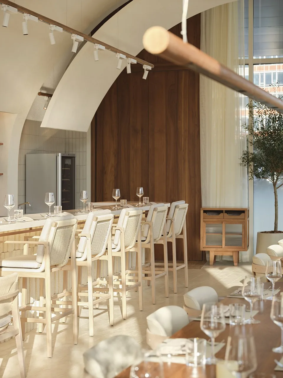 Modern restaurant interior with wooden tables, glassware, and stone accents.