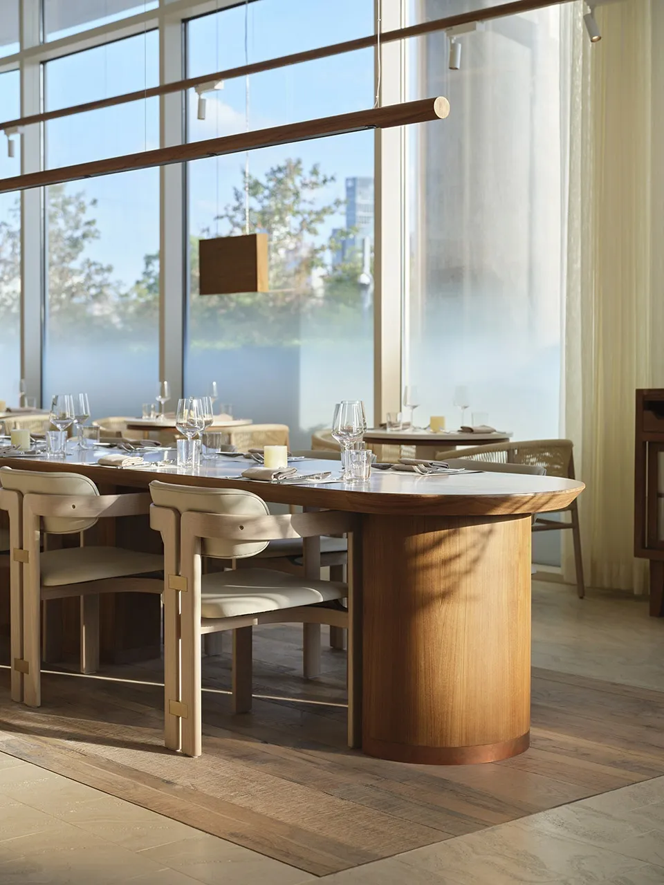 A modern restaurant interior featuring wooden tables and chairs with white plastic seats.
