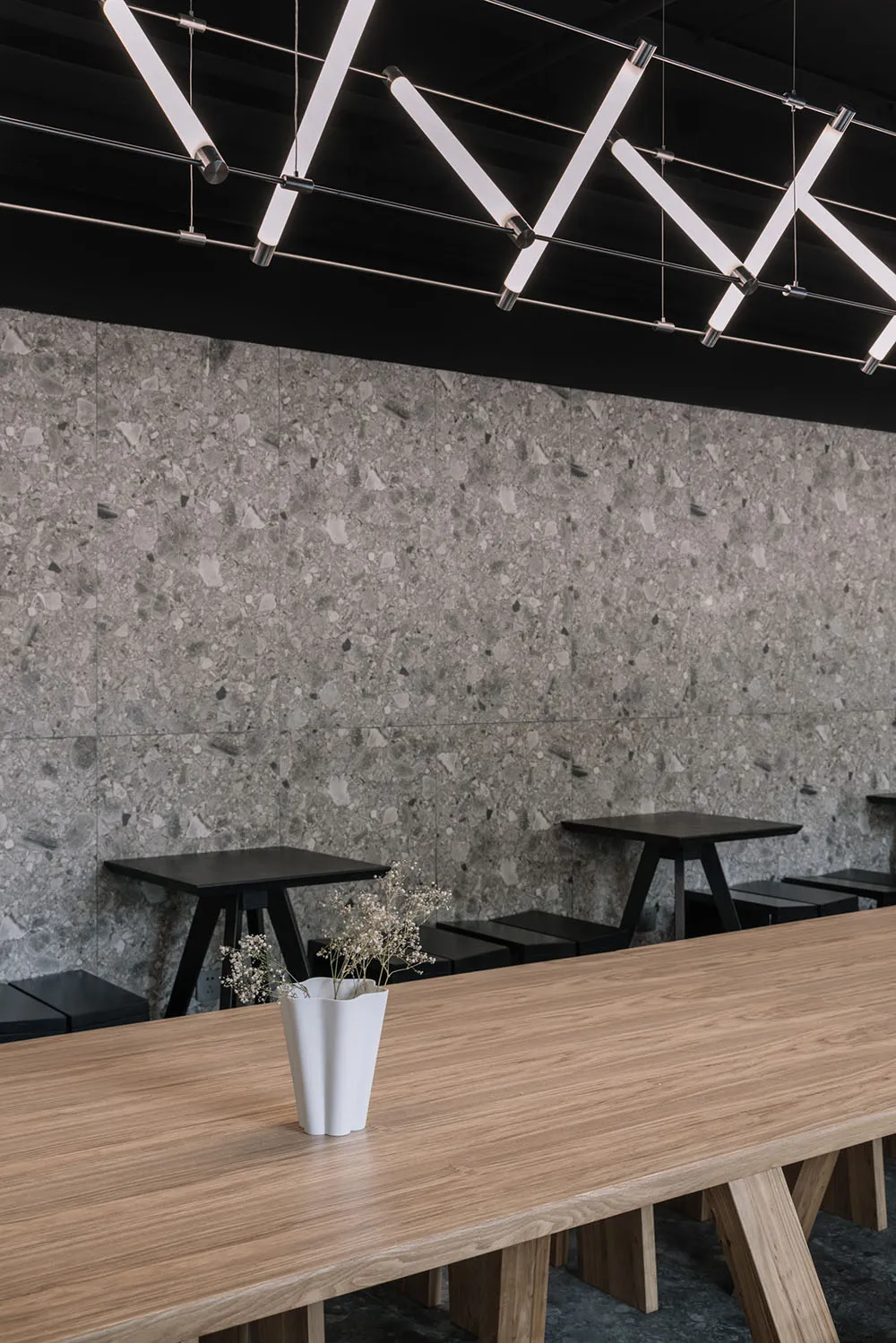 Industrial-style cafe interior with a terrazzo wall and wooden table.