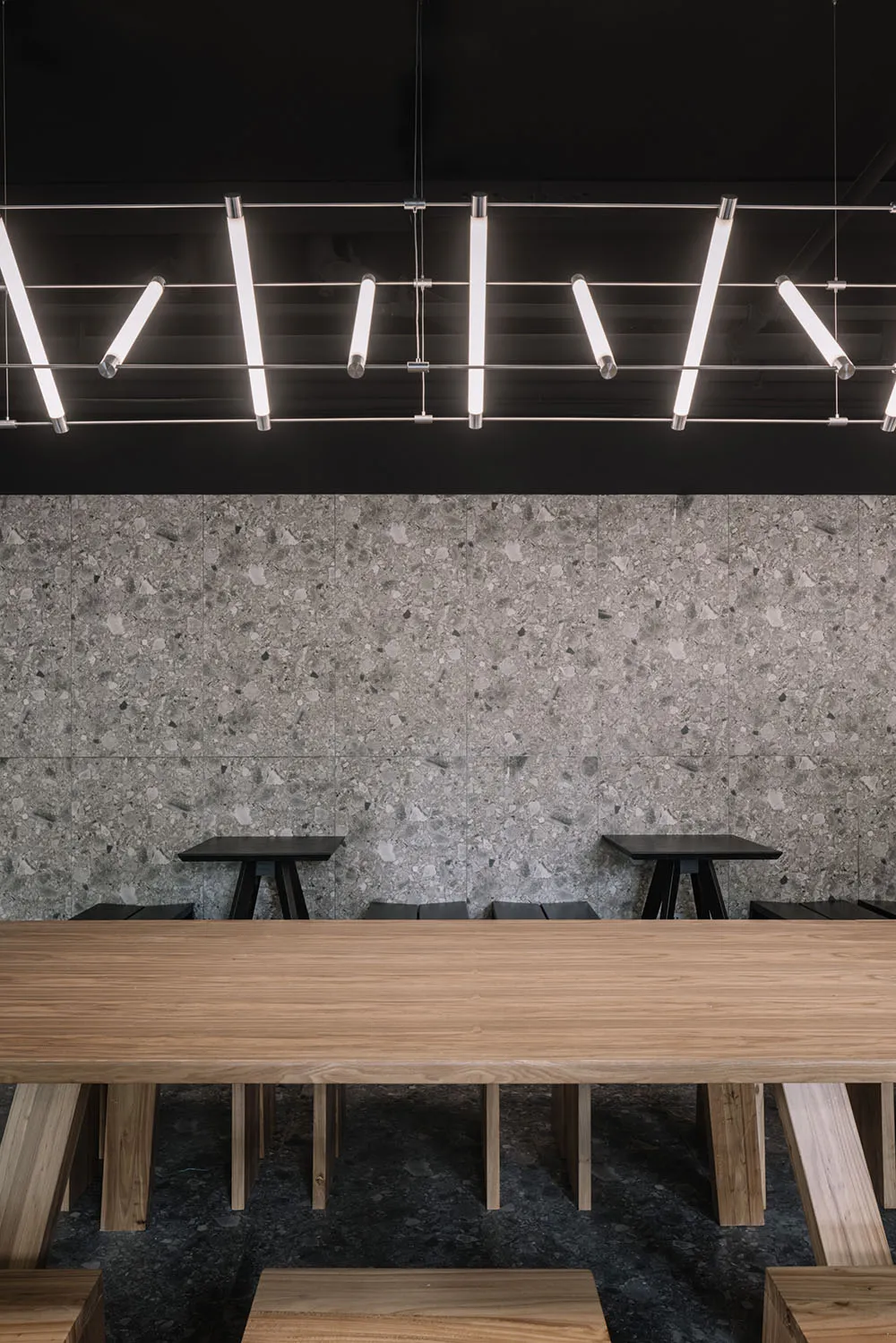 Modern coffee shop interior with concrete flooring, wooden furniture, and minimalist design.