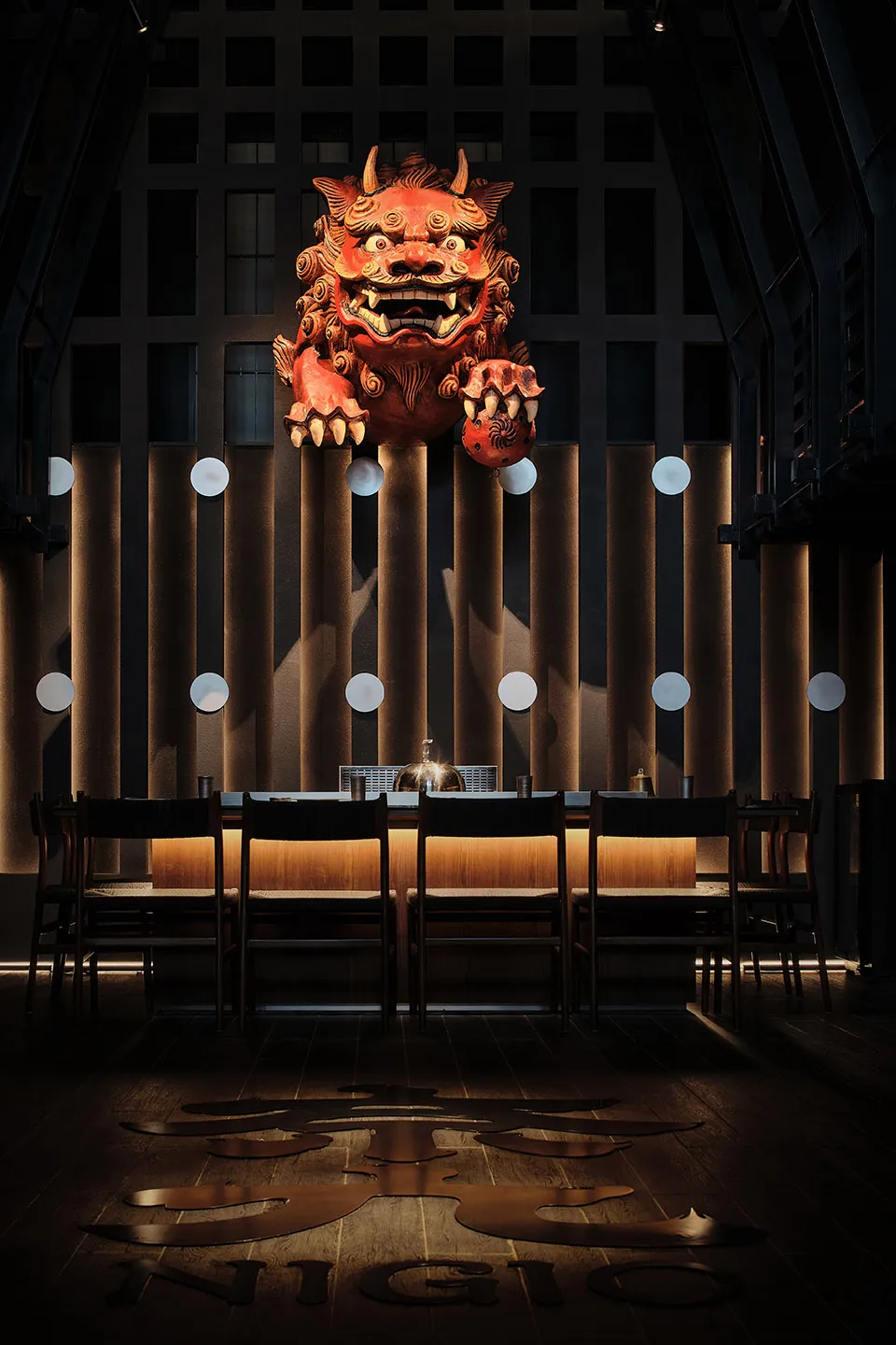 A modern bar interior with wooden accents, featuring a large red mascot statue.