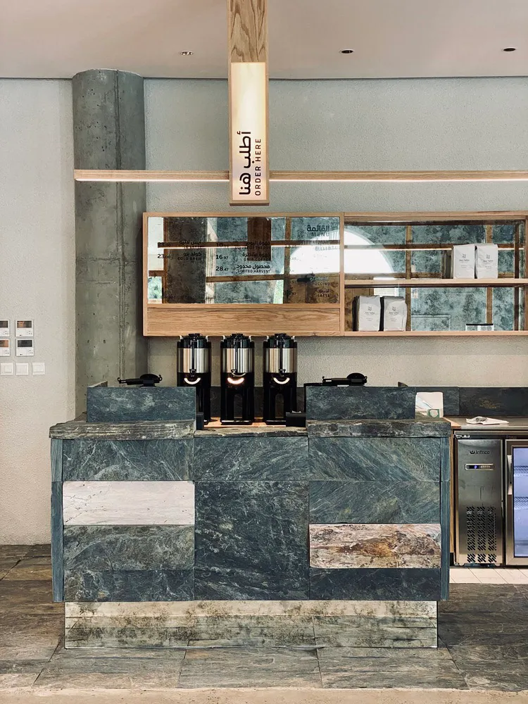 An image of a modern coffee shop interior with a marble and concrete counter.