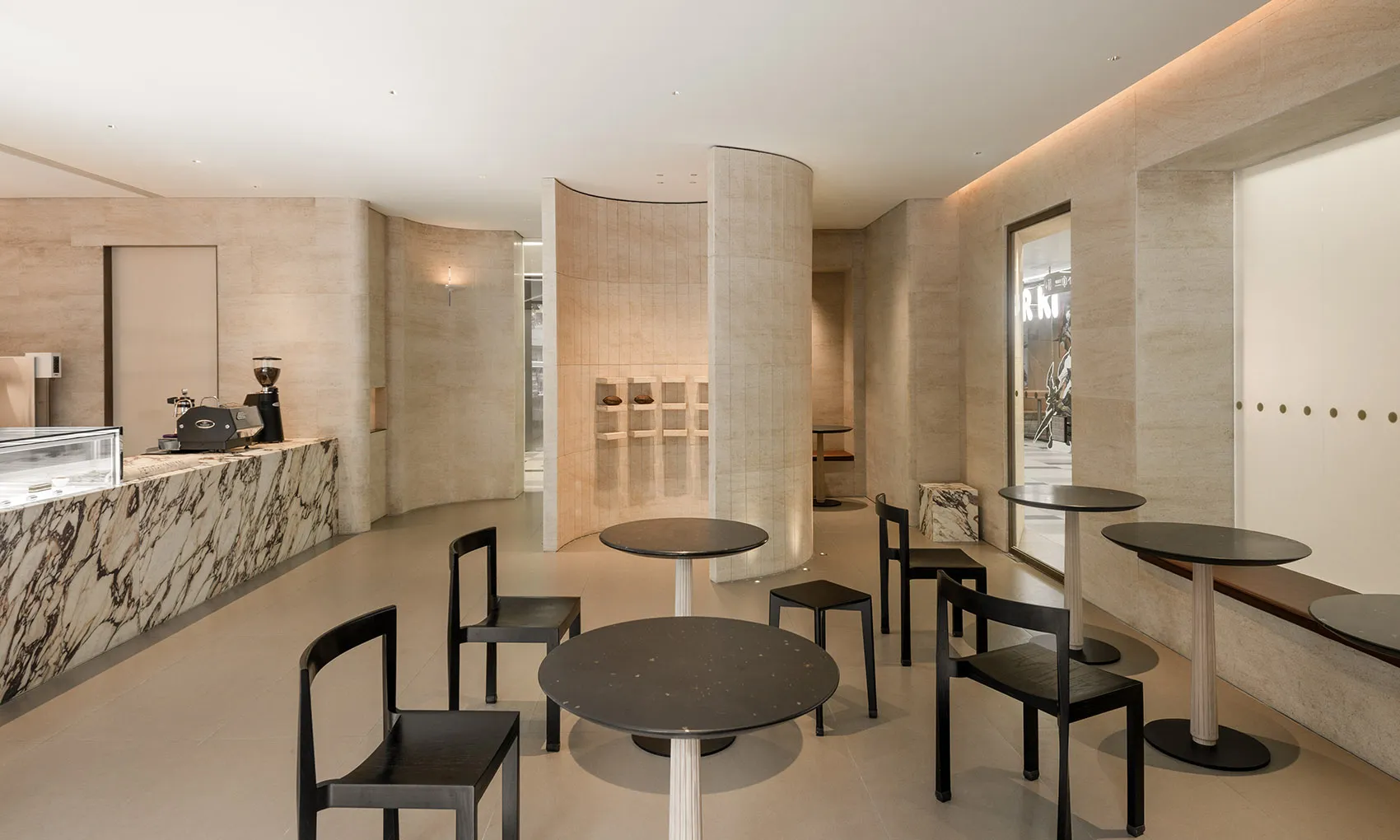 A modern coffee shop with minimalist design, featuring ceramic tiles and marble columns.