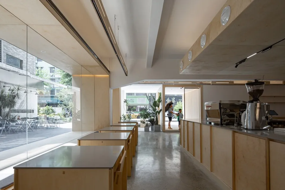 A modern minimalist coffee shop interior with wooden tables and a sleek, open design.