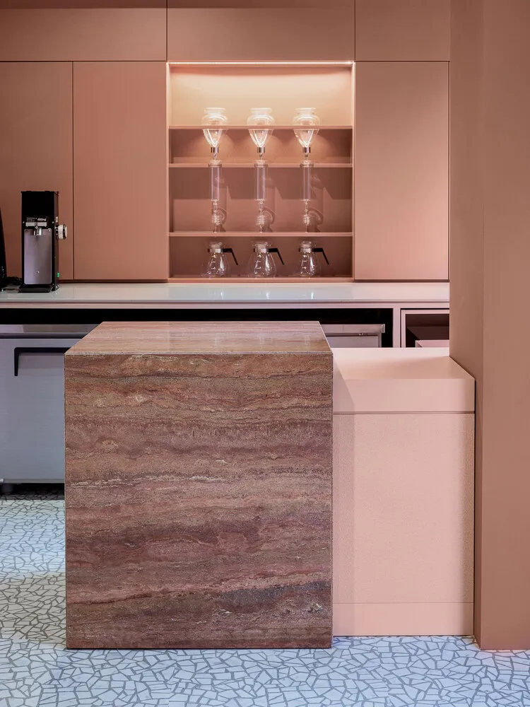 Modern minimalist kitchen with a marble countertop and pink cabinets.