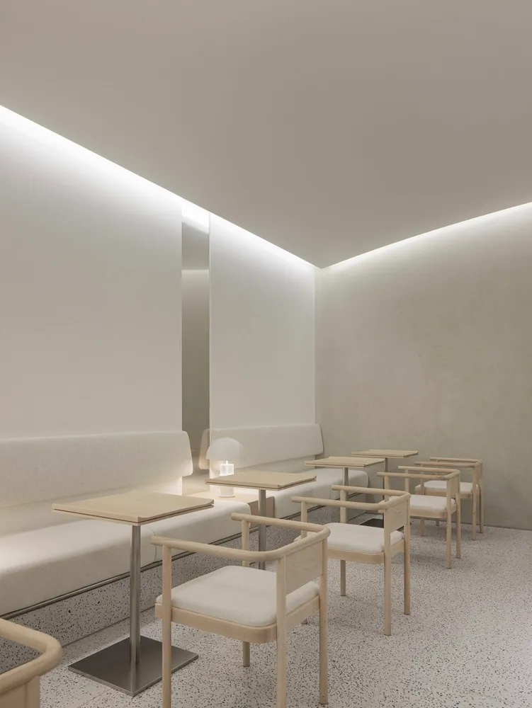 以白色為主的餐廳室內,採用極簡設計,搭配木製椅與布面座椅。
