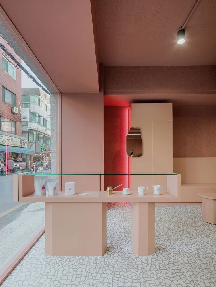 Modern retail coffee shop interior with contemporary pink and red accents and a glass counter featuring coffee-related produc