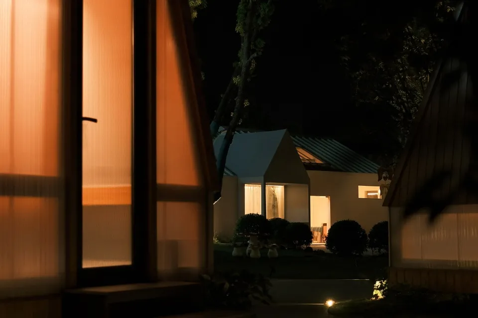A modern residential exterior with wooden elements and white curtains.