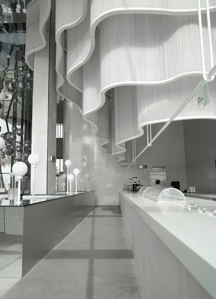 A modern bar interior featuring metallic accents, transparent glass elements, and concrete surfaces.