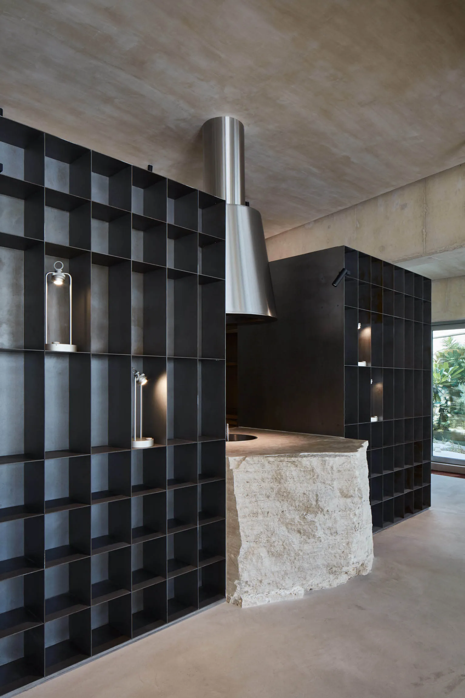 A modern kitchen with black tiles and concrete countertops.
