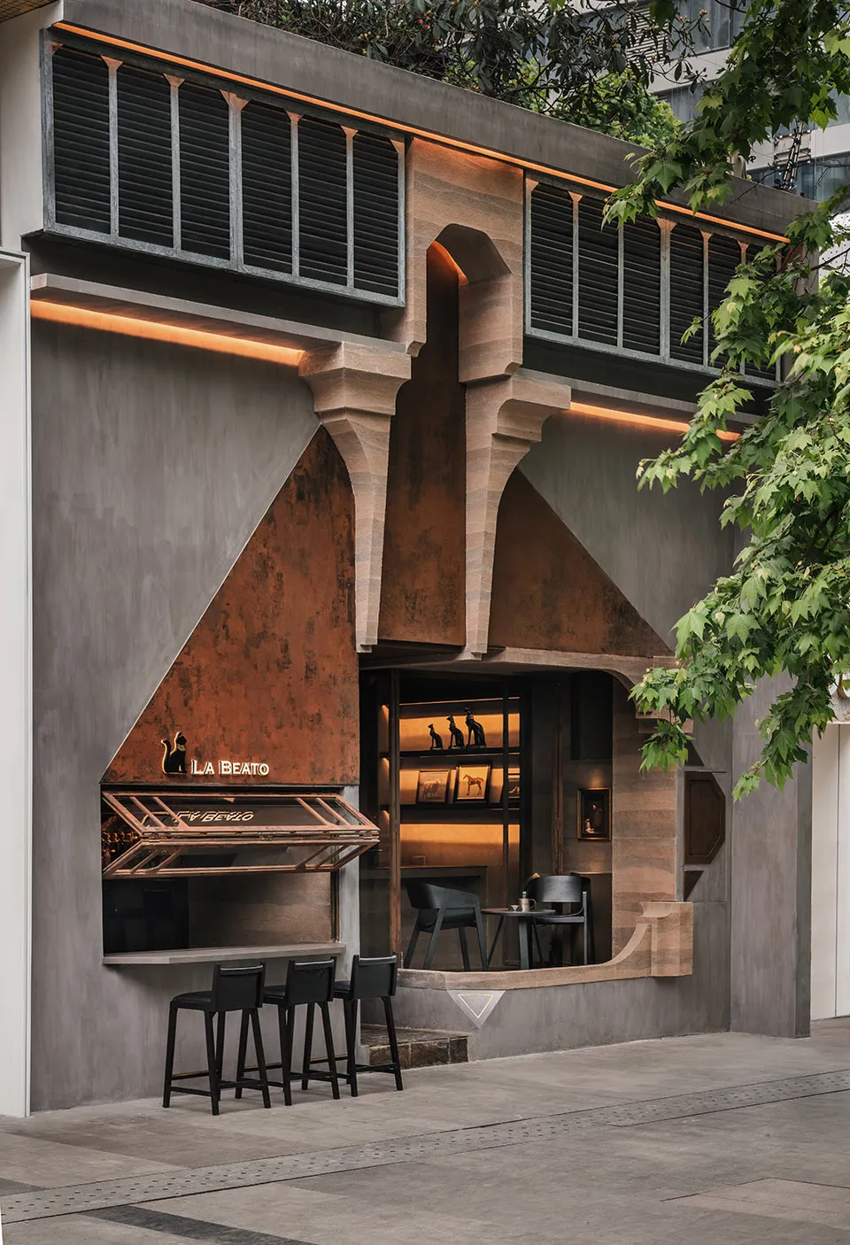 A modern cafe exterior with a concrete facade and arched windows, featuring a bar counter with stools.
