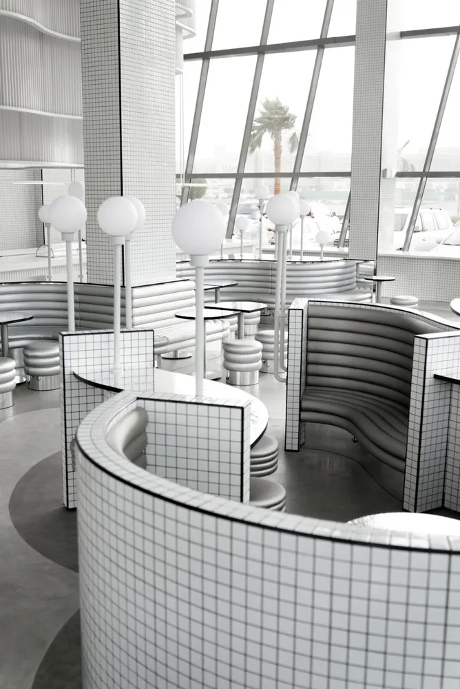 Modern restaurant interior with white grid tiles on walls and curved benches