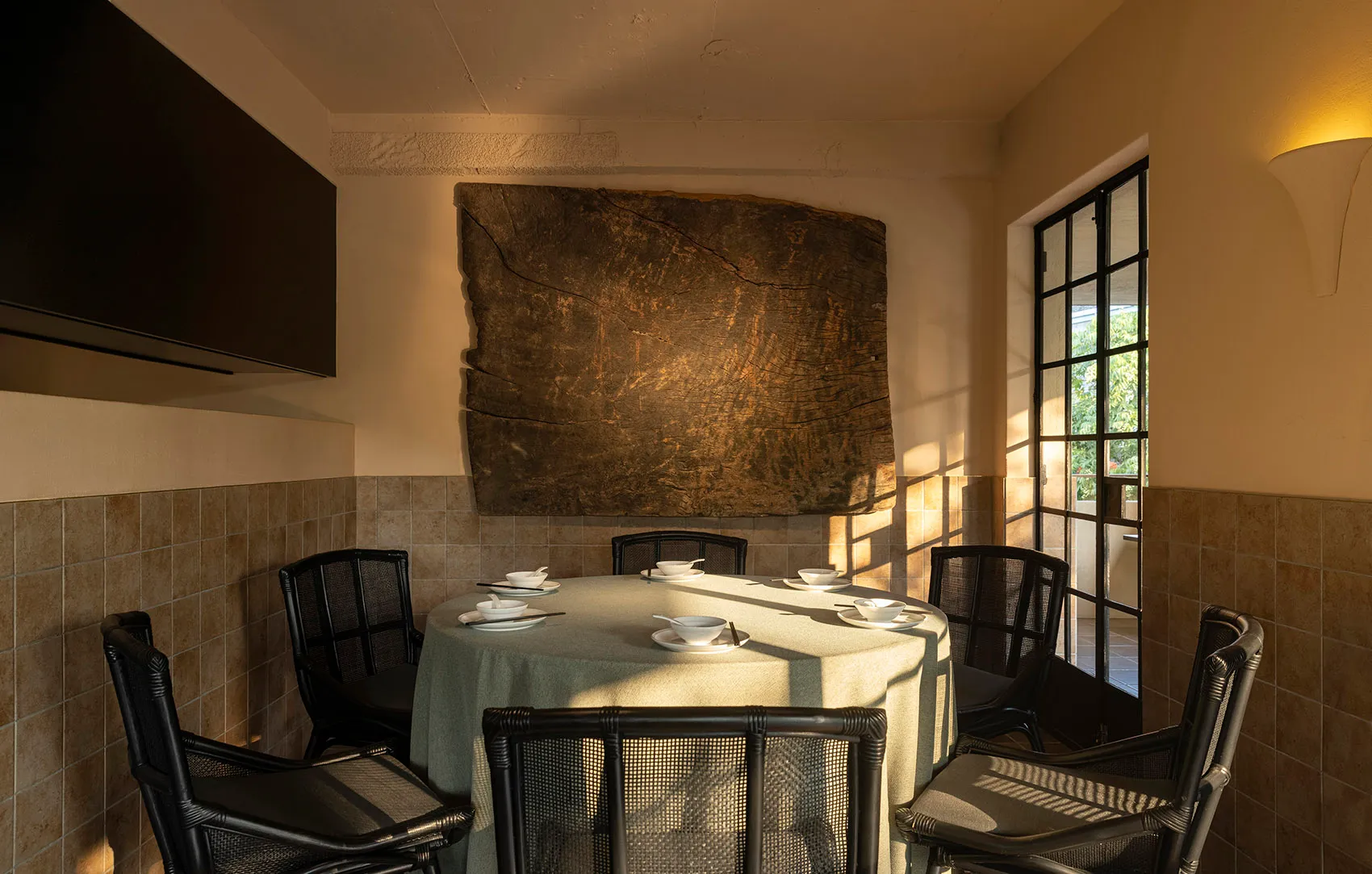A modern indoor dining room with a concrete wall and a round dining table.