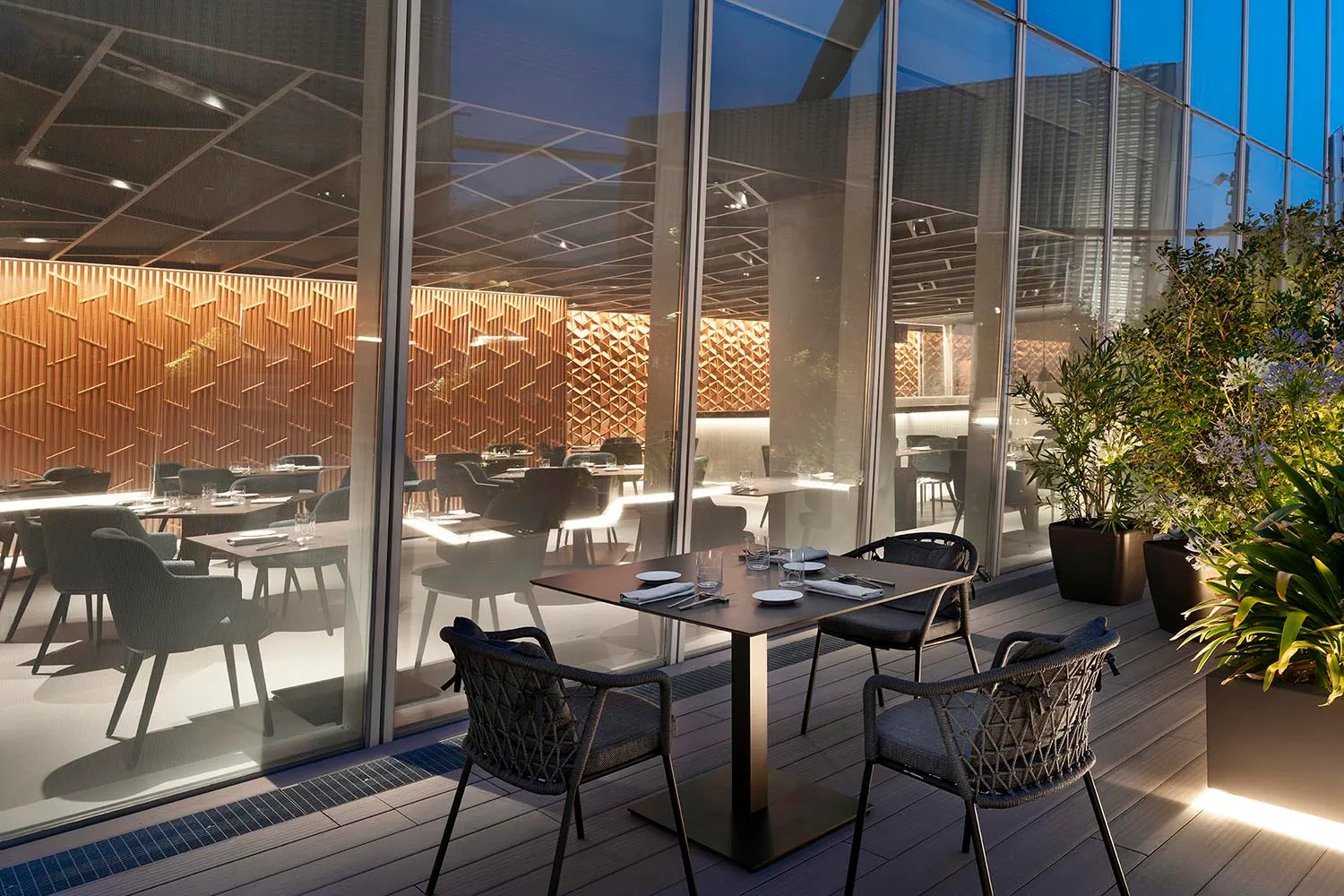 Modern luxury dining room with wooden paneling and glass furnishings, featuring sleek design and elegant atmosphere.