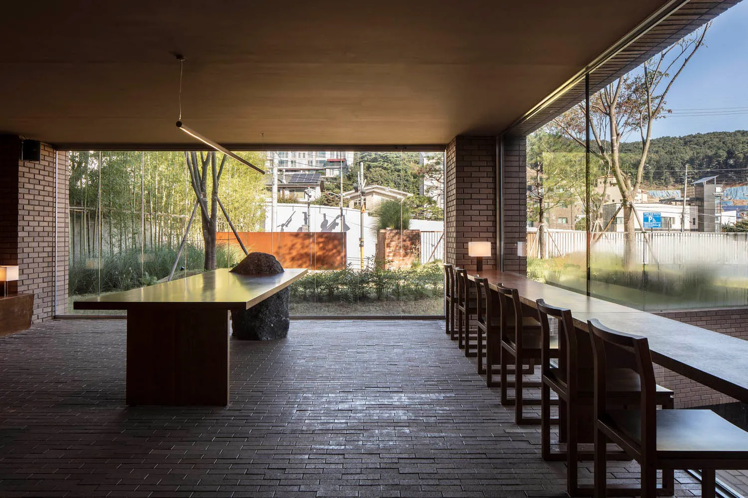 A modern café interior with brick walls, concrete flooring, and large glass windows.