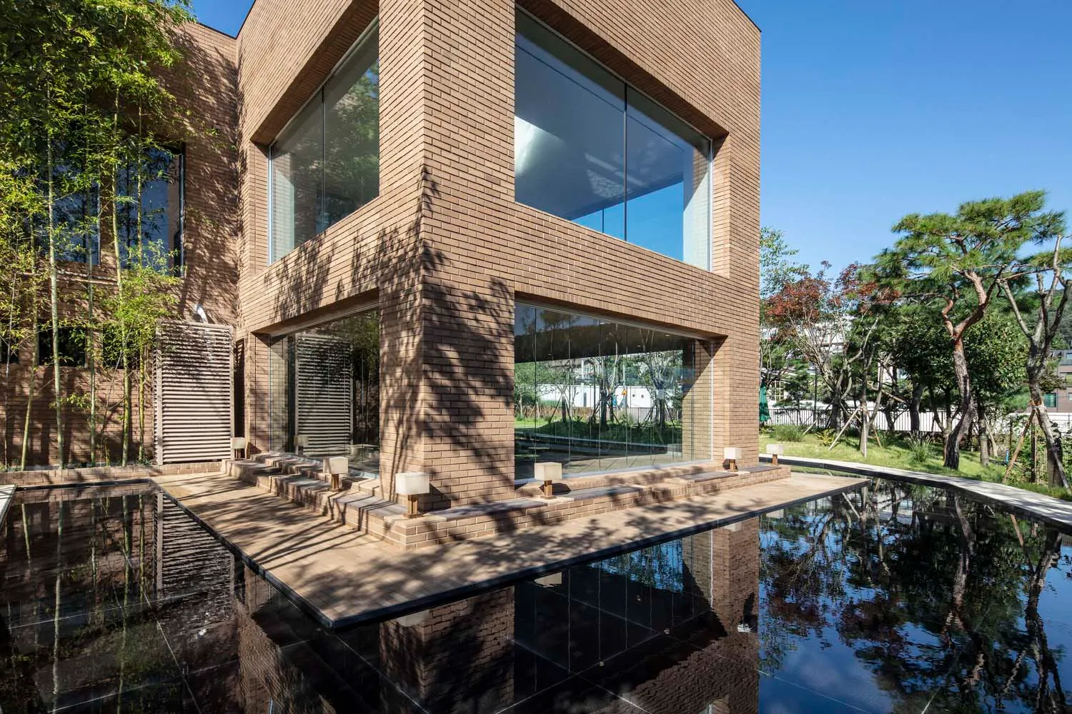Modern building constructed with brick, featuring large glass windows and a reflection pool.