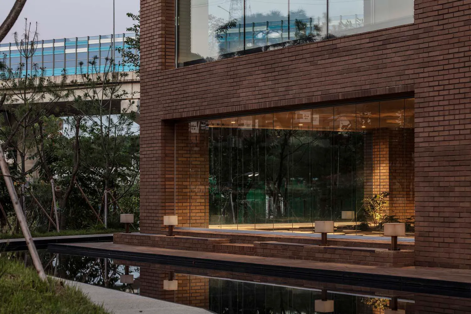 Modern residential exterior with brick cladding and large glass windows reflecting the surrounding environment.