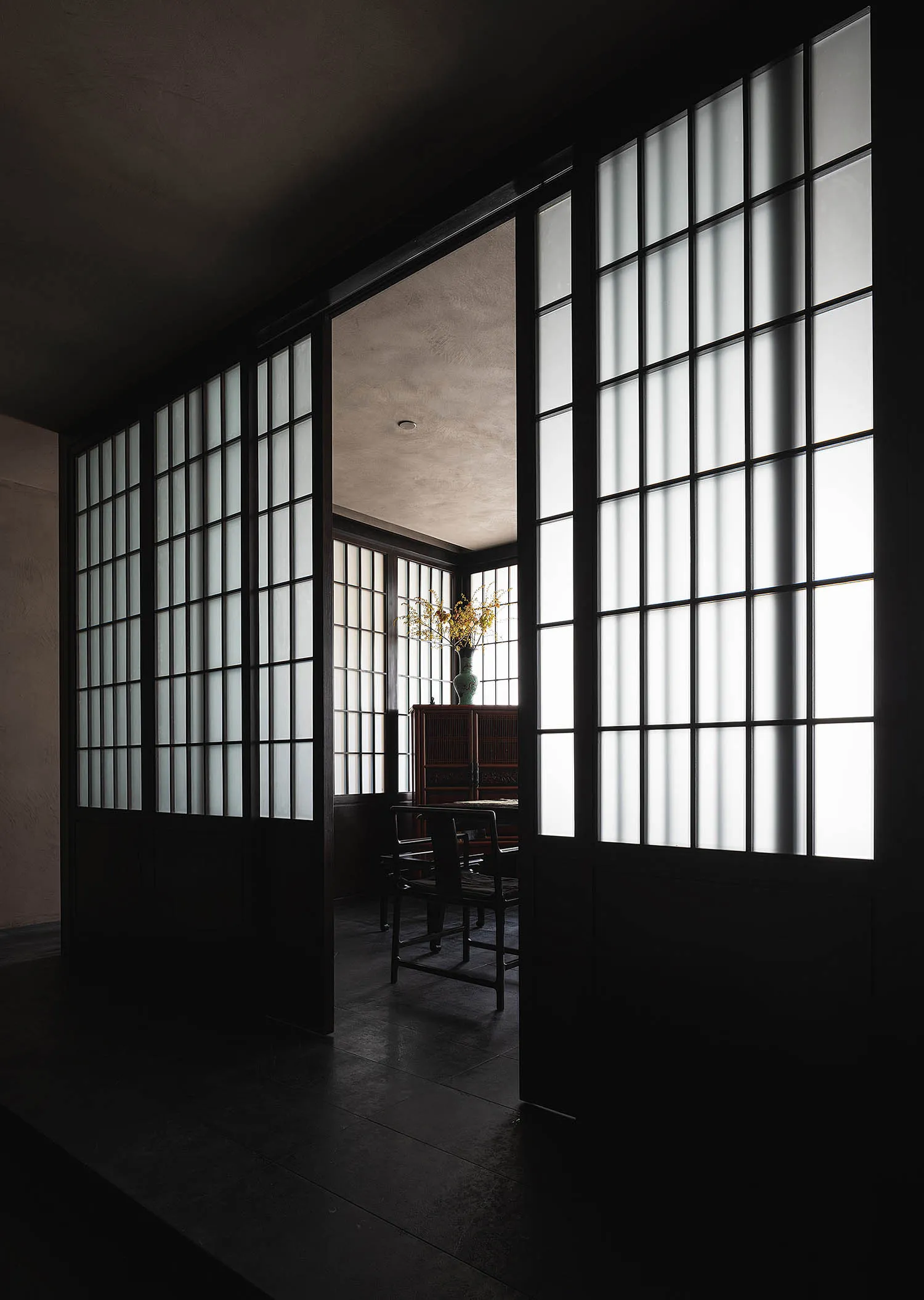 A minimalist room featuring white windows, wooden flooring, and simple furniture.