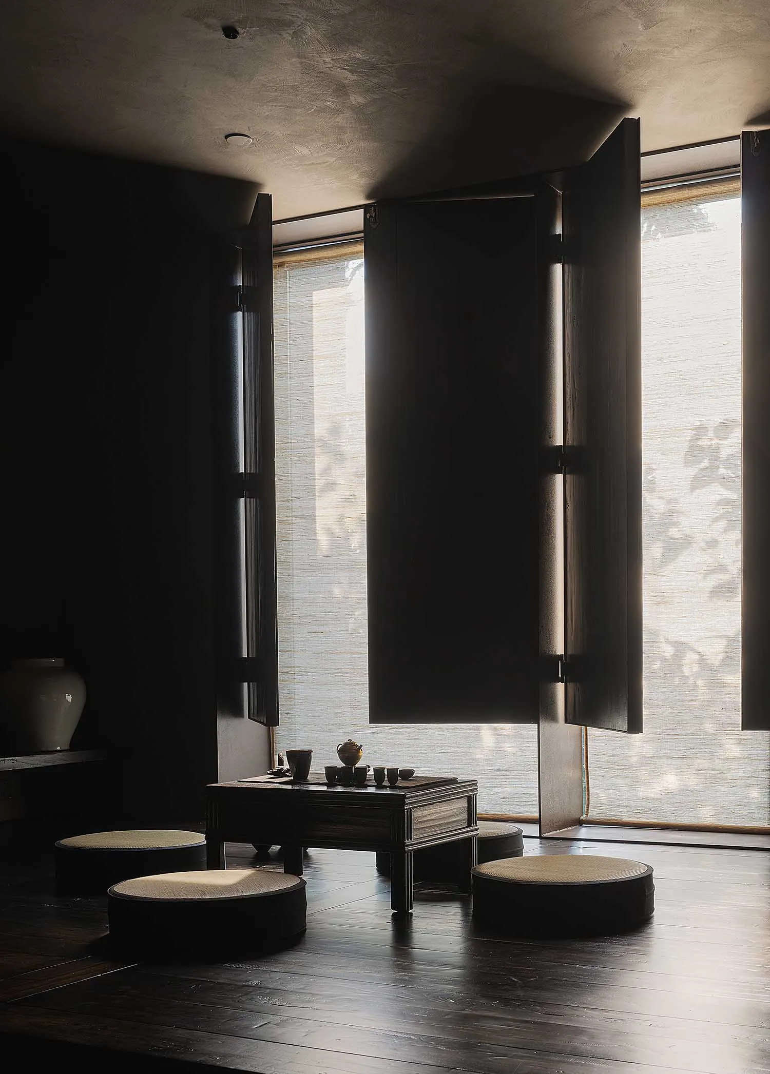 A minimalist tea room with wooden furniture and fabric cushions.