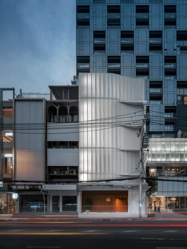 A modern retail storefront with a glass facade and marble platform showcasing products.