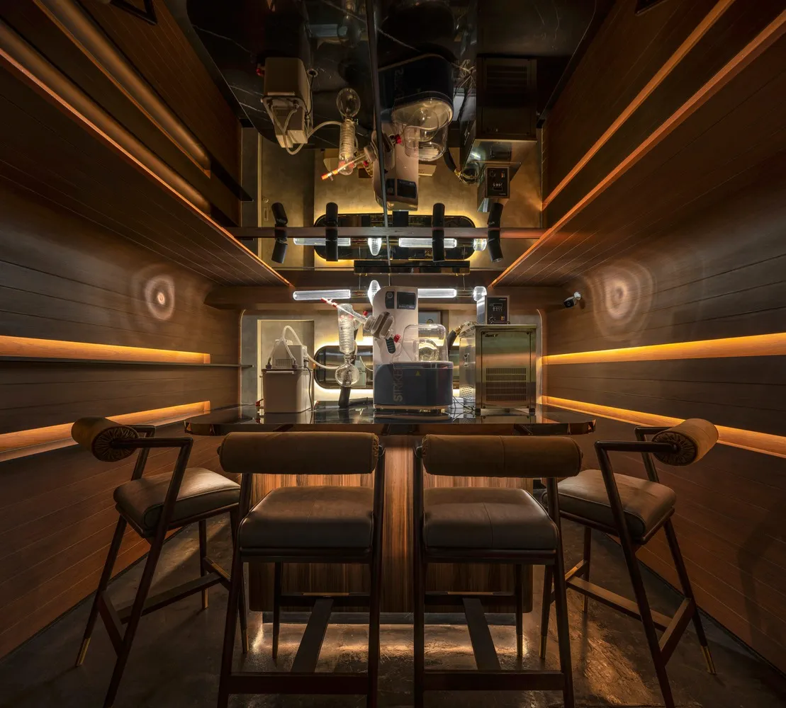 Industrial-style bar with metal stools, glass tubes, and industrial equipment.