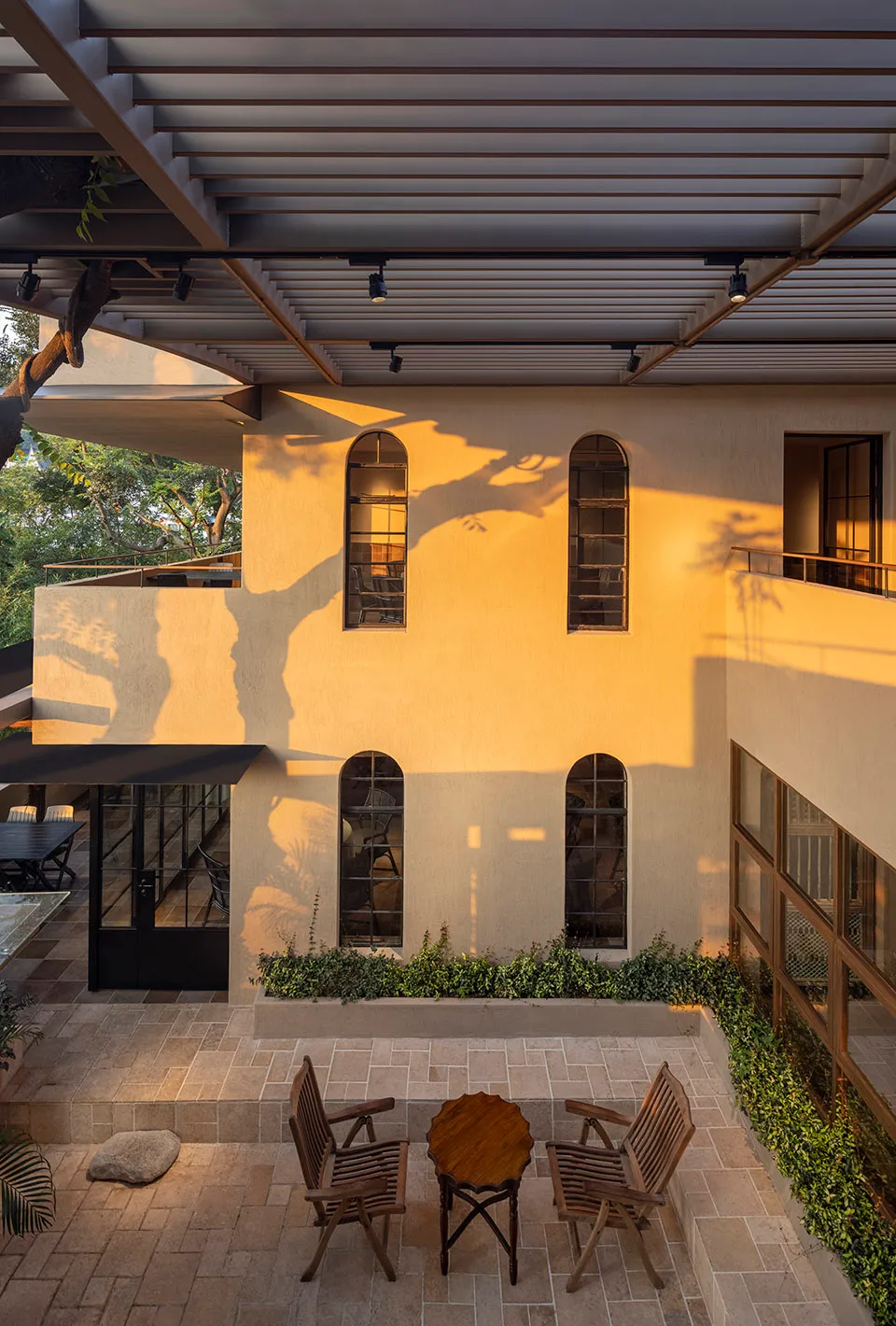 Concrete patio with ceramic tiles, wooden furniture, and glass wall.