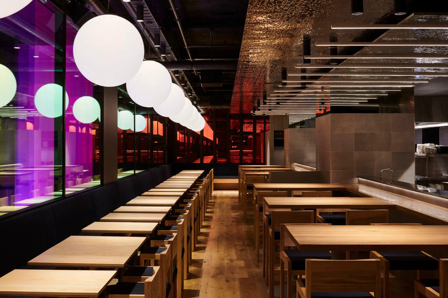 A modern restaurant interior featuring wooden furniture and contemporary lighting design.