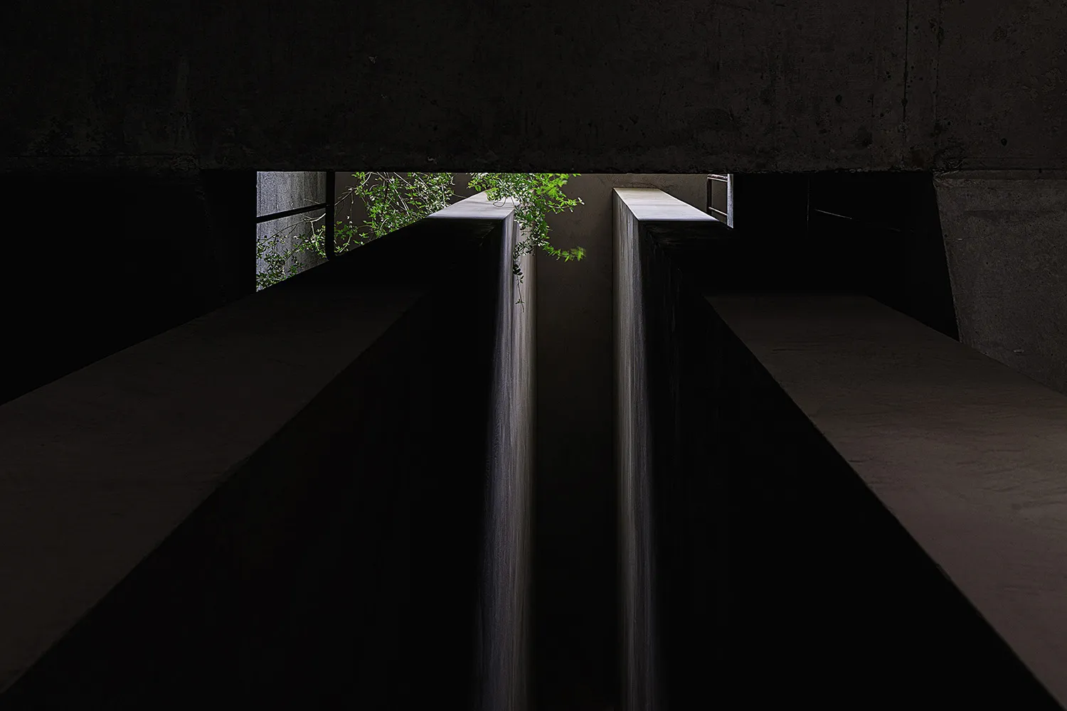 A dark, minimalist concrete interior with a black background and water-like features.