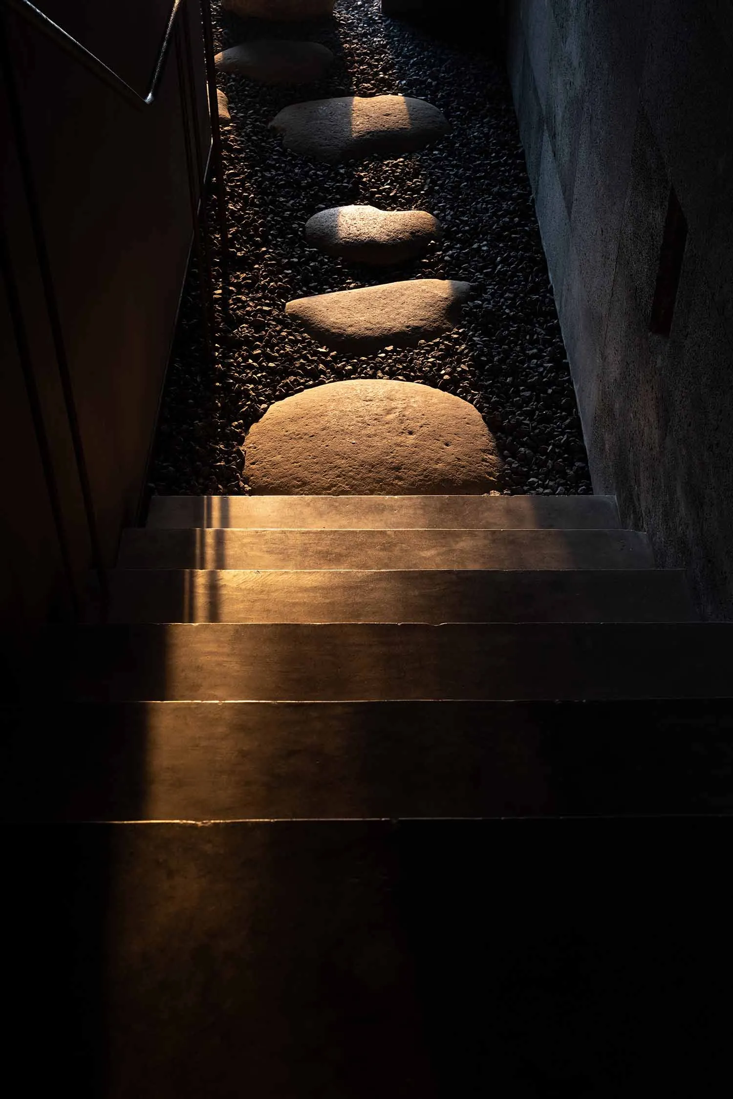 A modern entrance with concrete steps and rocks in a dark setting