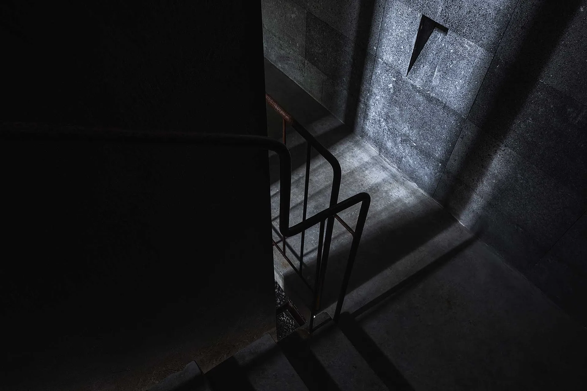 Industrial-style concrete stairs with metallic handrails and light filtering through a window.