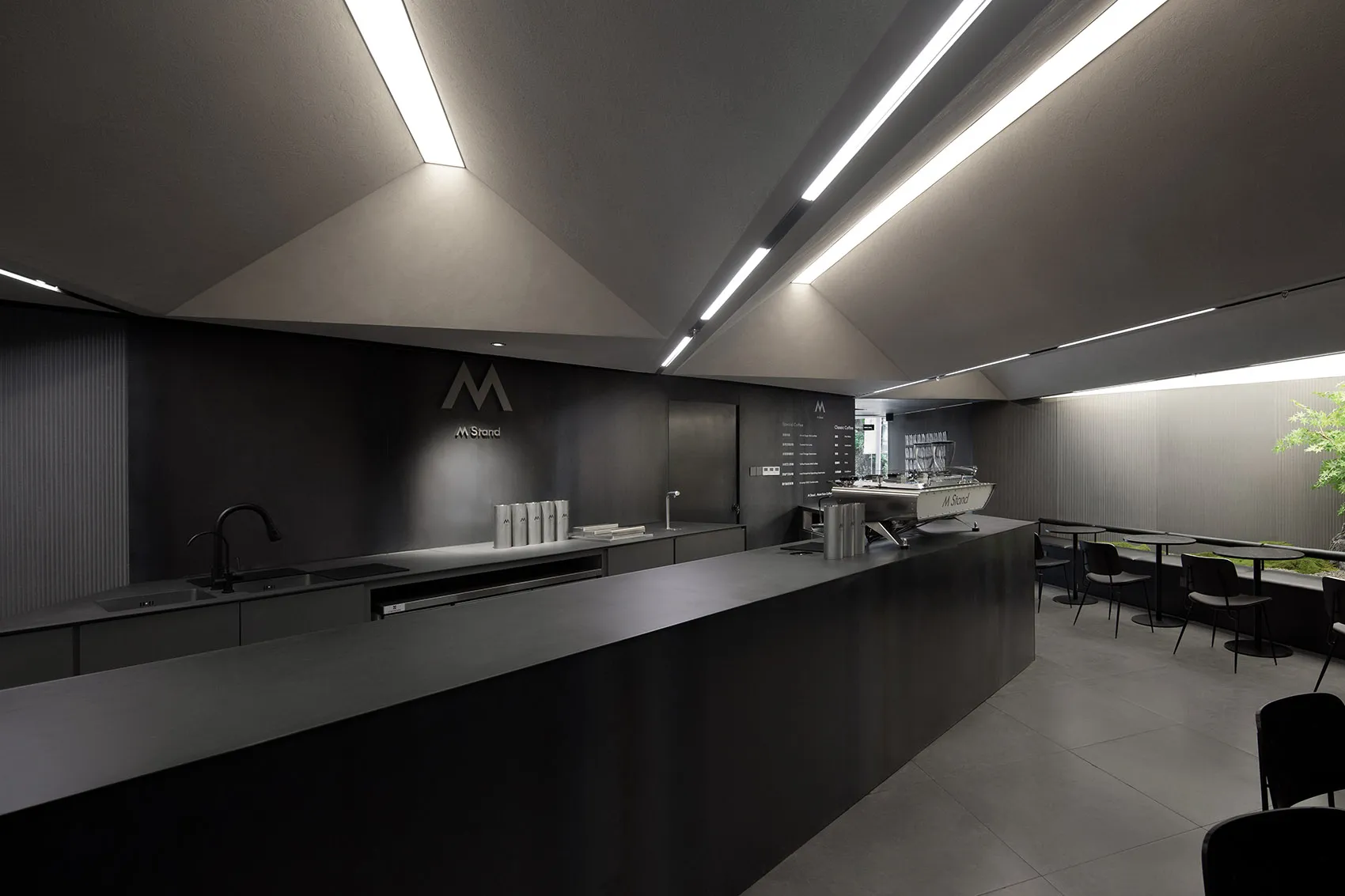 A modern, minimalist coffee shop with a sleek concrete counter and industrial lighting.