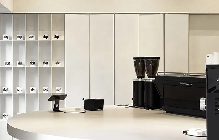A minimalist coffee shop with a granite countertop, coffee grinding machines, and neatly arranged containers.