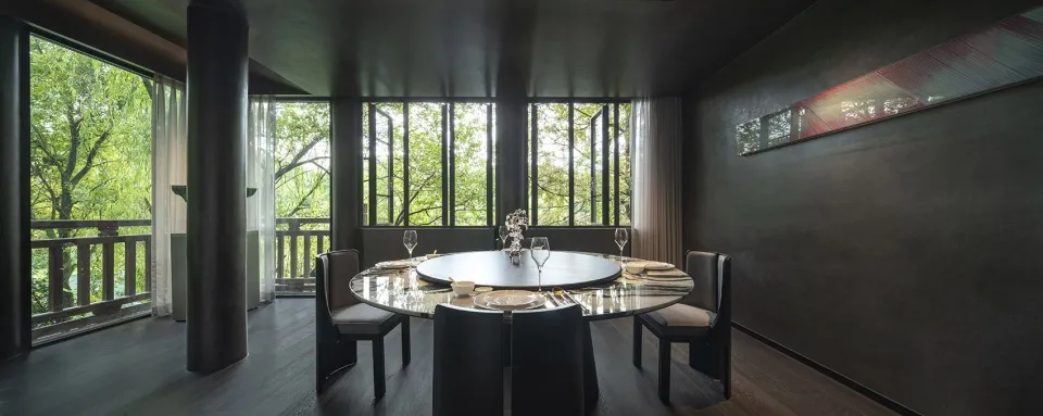 A modern dining room featuring a glass table surrounded by chairs and set with wine glasses, plates, and a centerpiece arrang