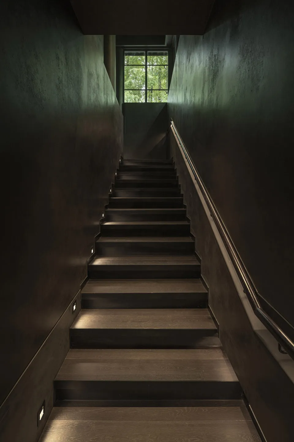 Modern industrial-style staircase with wooden steps, featuring minimalist design and an open area at the top with a view of g