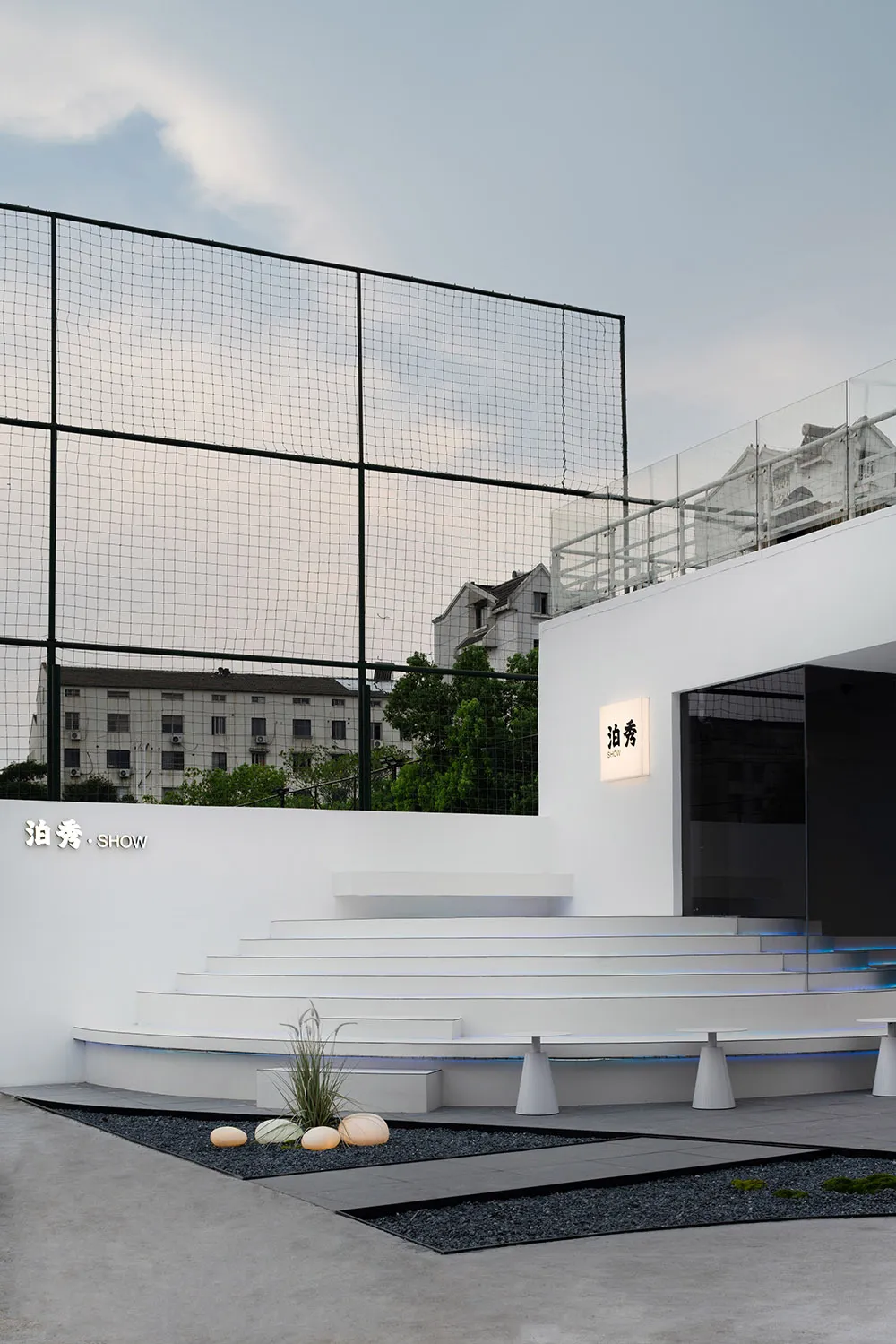 Outdoor modern public space with concrete steps, black gravel, and a black fence.